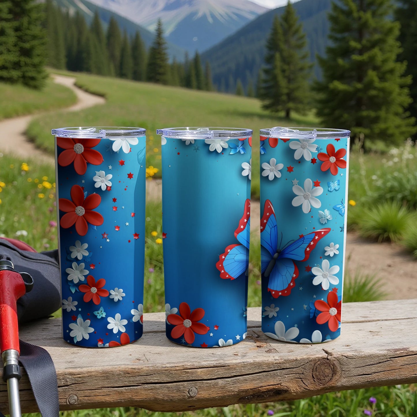 Three blue tumblers with red and white flowers and a butterfly design.