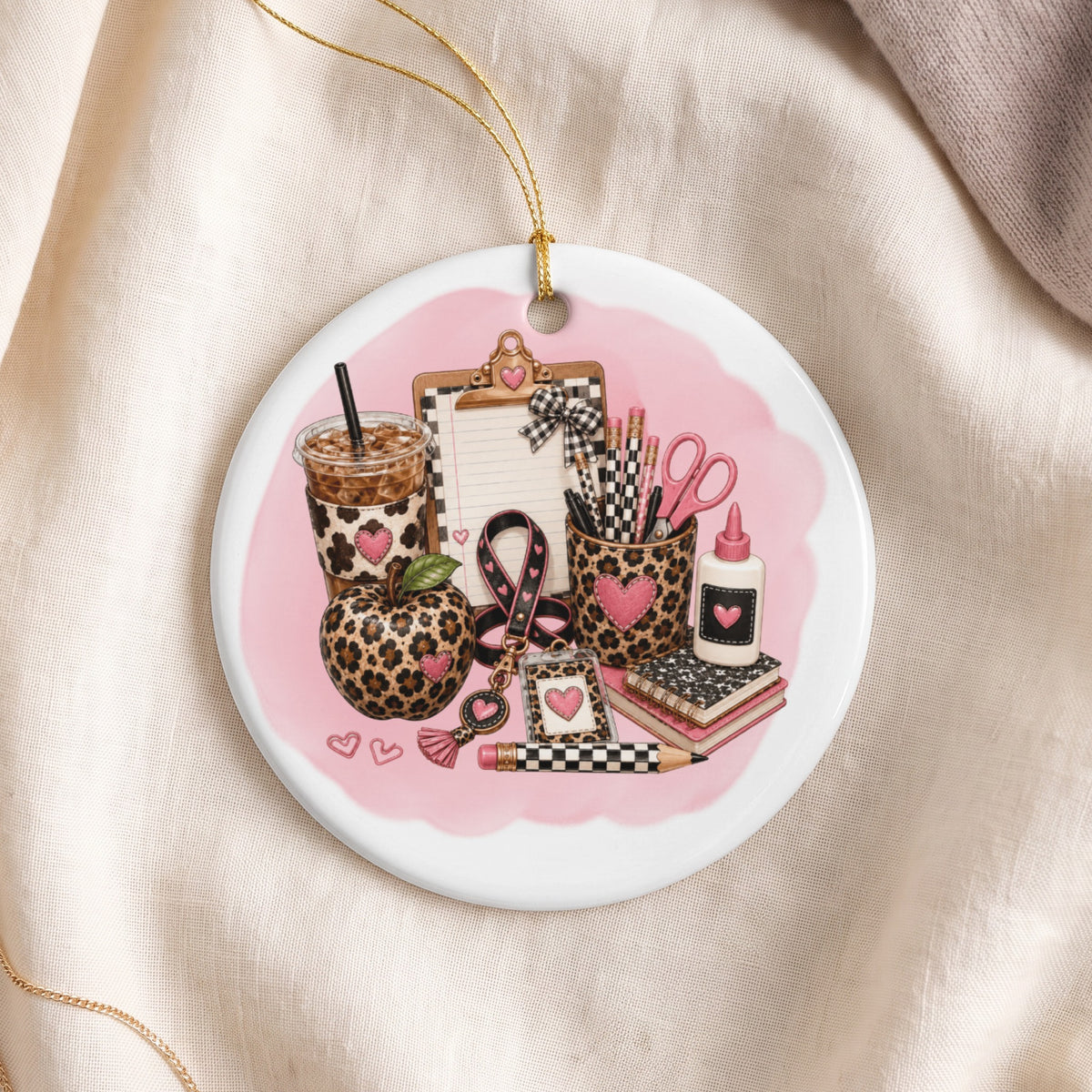 Leopard print school supplies and apple adorn a circular ornament on a pink background.