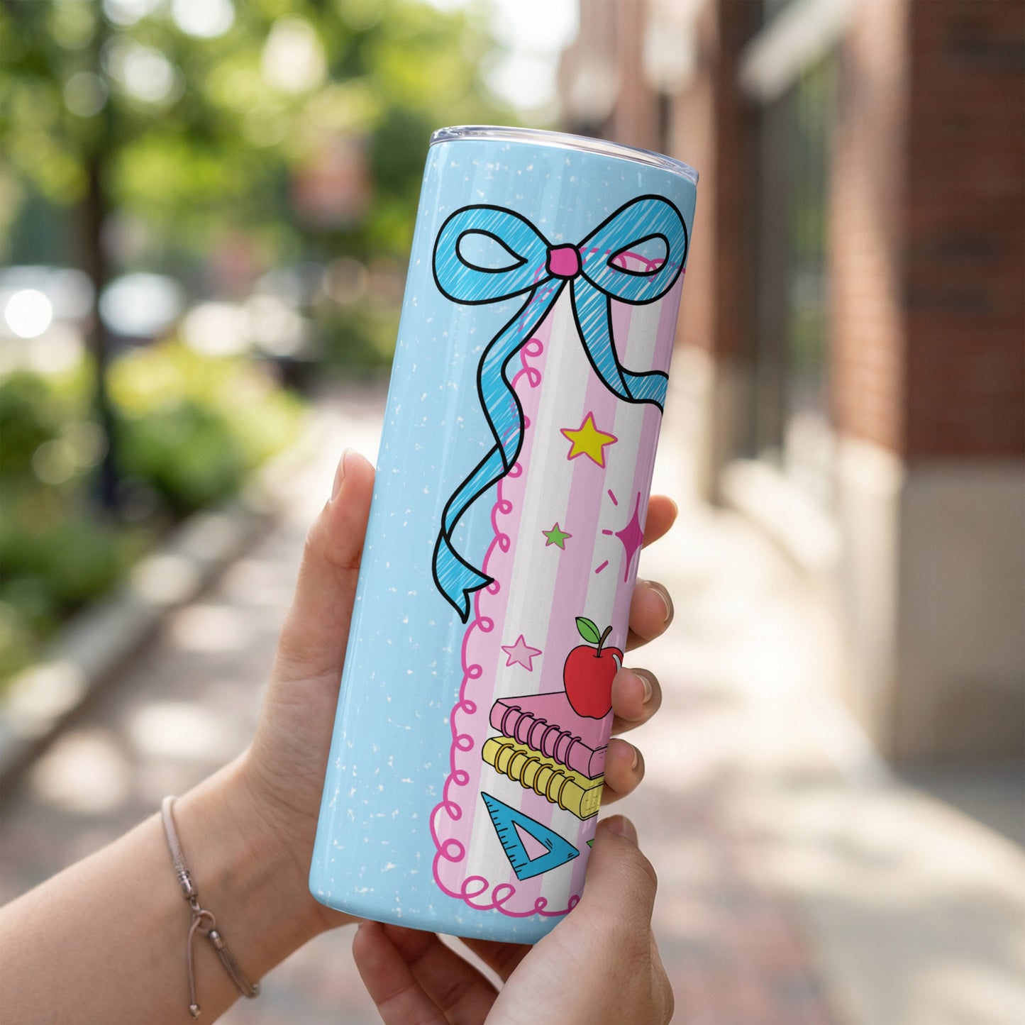 Light blue tumbler with a blue bow, books, apple, ruler, and stars design.