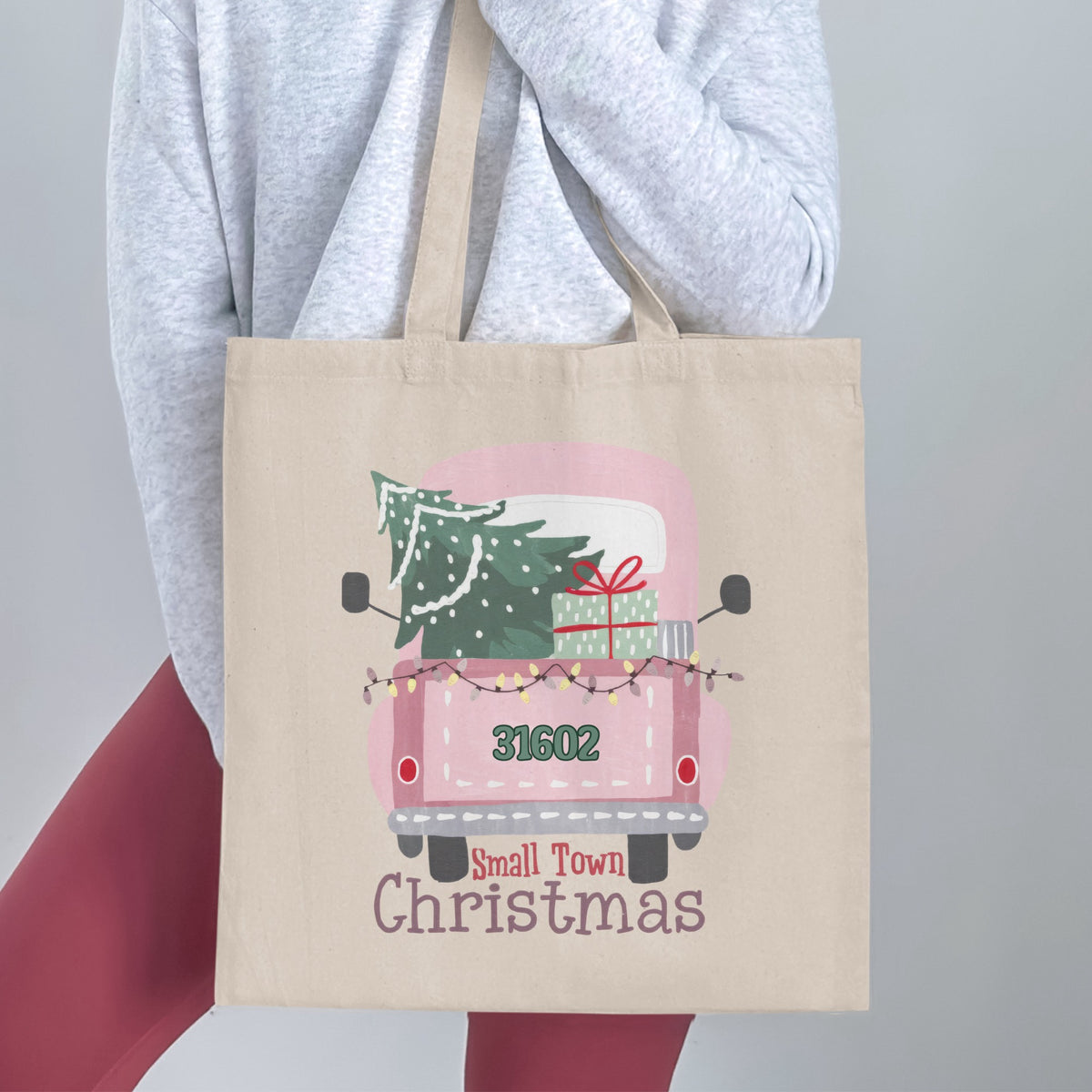 Tote bag with a pink truck, Christmas tree, presents, and text "Small Town Christmas".