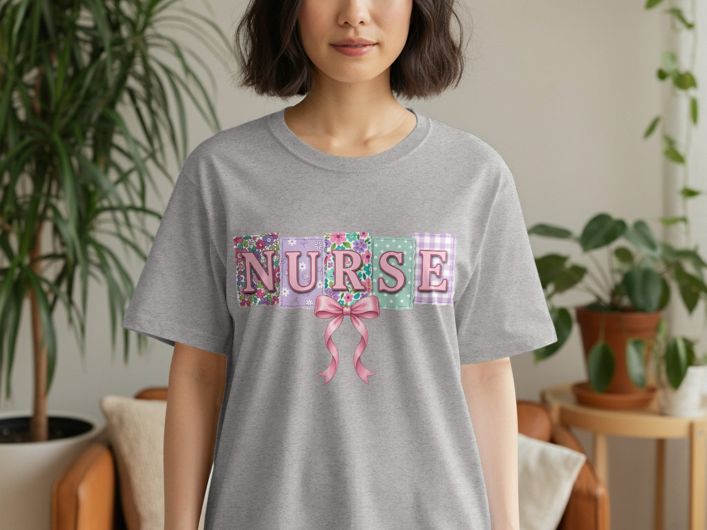 Grey t-shirt with "NURSE" in pastel floral letters and a pink bow.