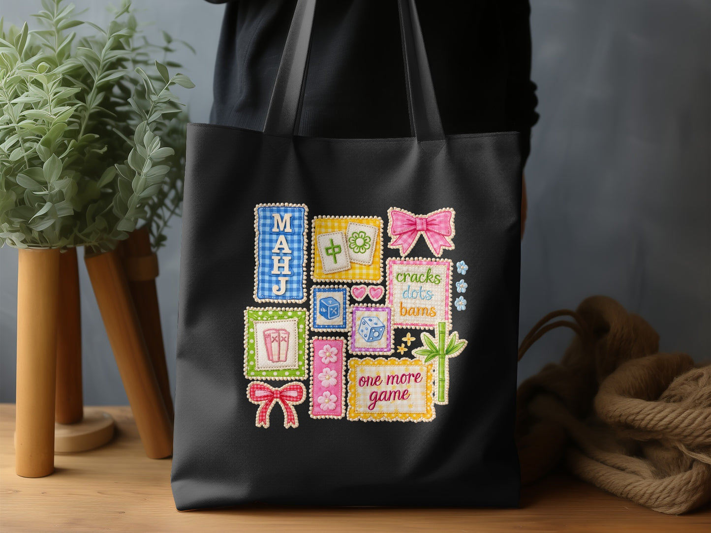 Black tote bag with embroidered mahjong tiles, dice, bows, and text.