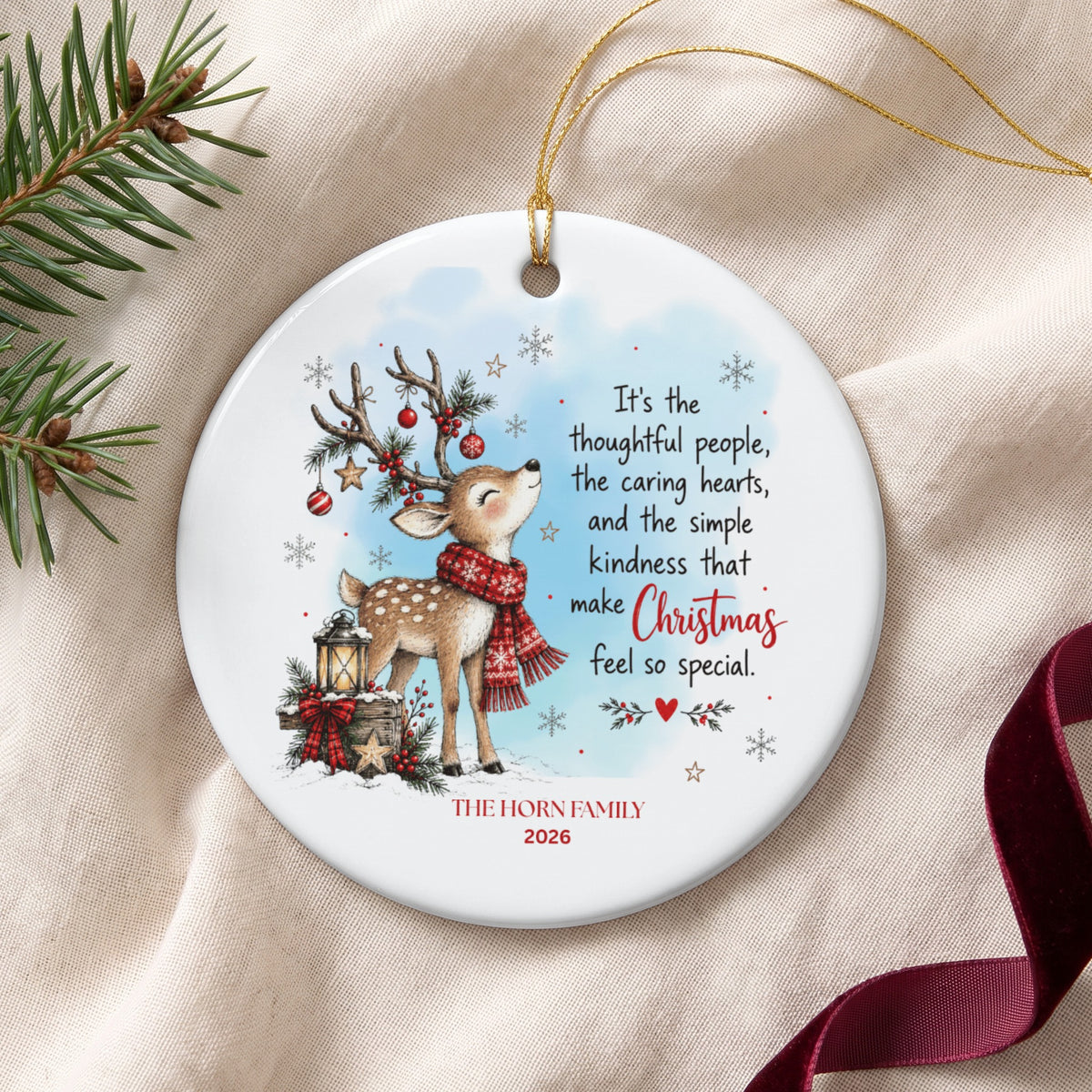 A round ceramic Christmas ornament featuring a fawn, a lantern, festive text, and personalization.