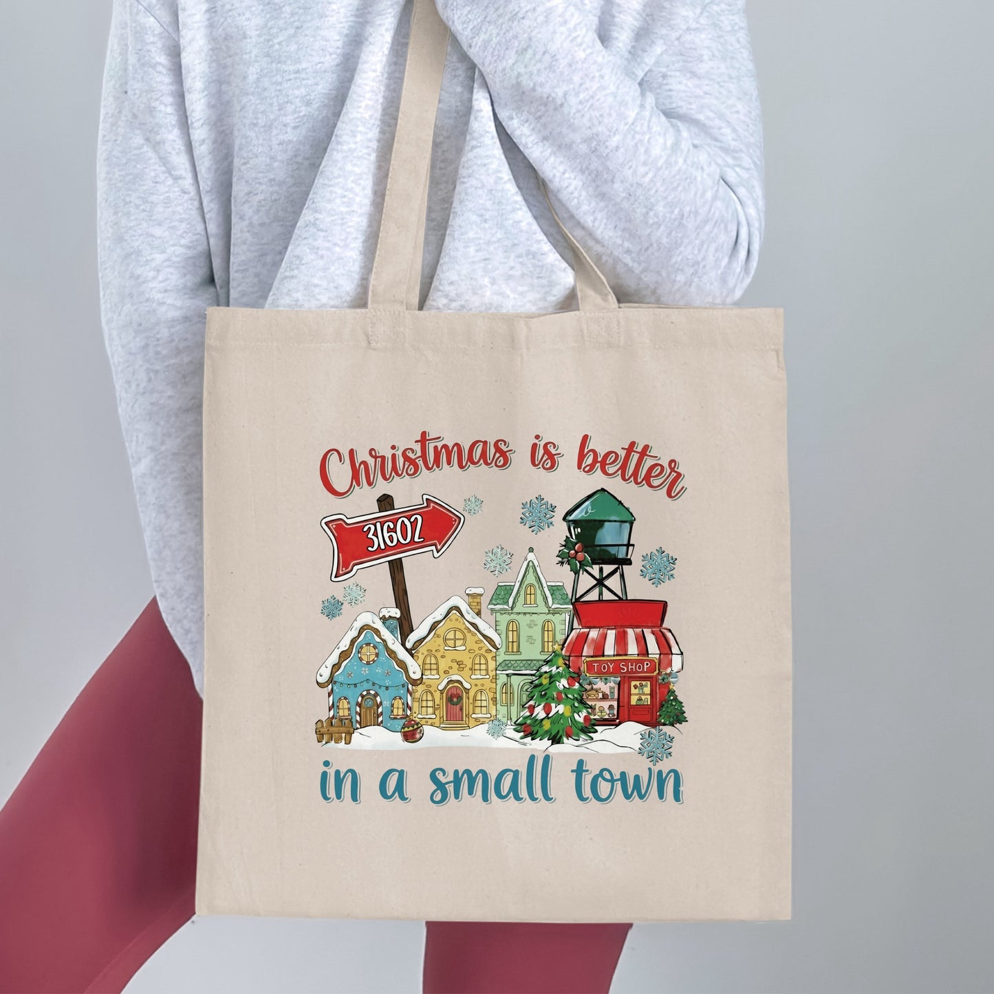 Tote bag with a Christmas town scene and the text "Christmas is better in a small town".