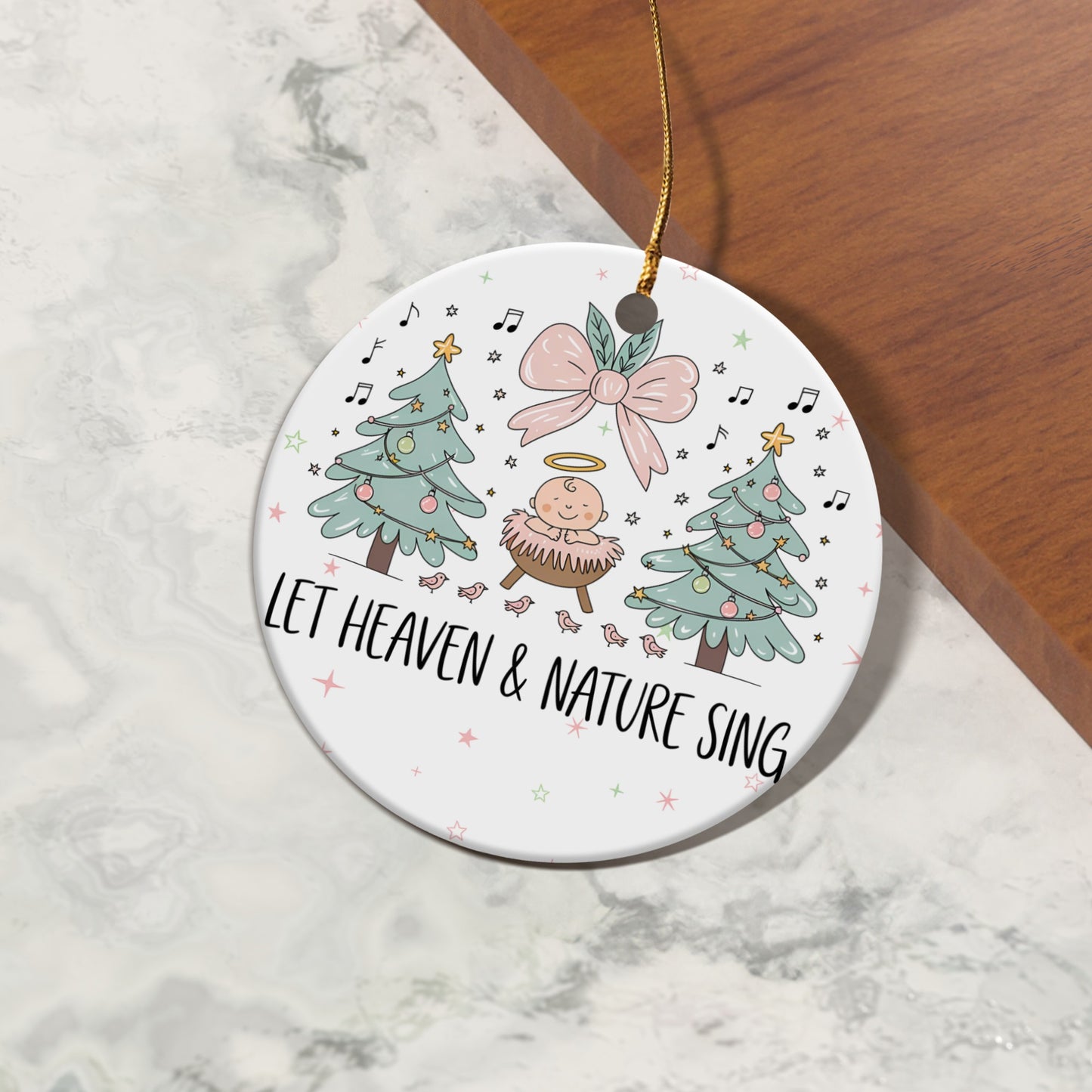 Round ornament with baby Jesus, Christmas trees, and text "LET HEAVEN & NATURE SING".