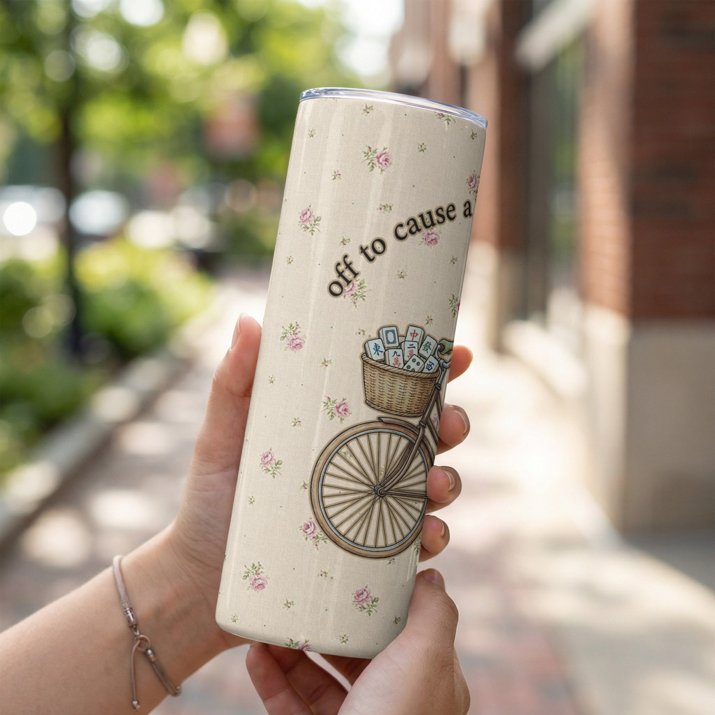 Cream tumbler with floral pattern, bicycle basket, and "off to cause a scene" text.