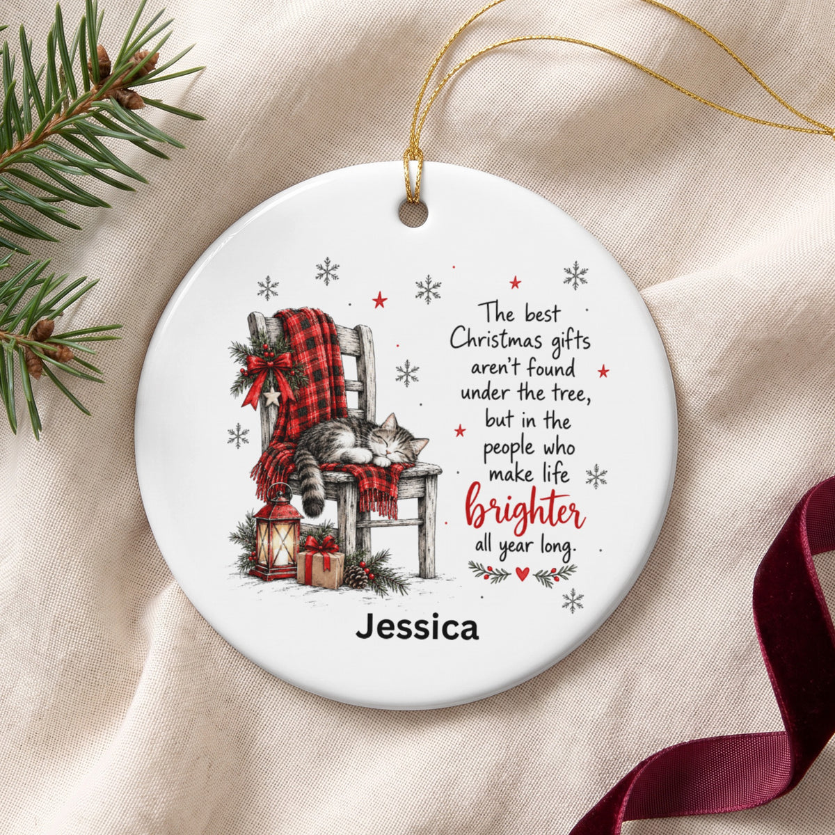 Round ceramic ornament featuring a sleeping cat on a chair, holiday text, and the name Jessica.