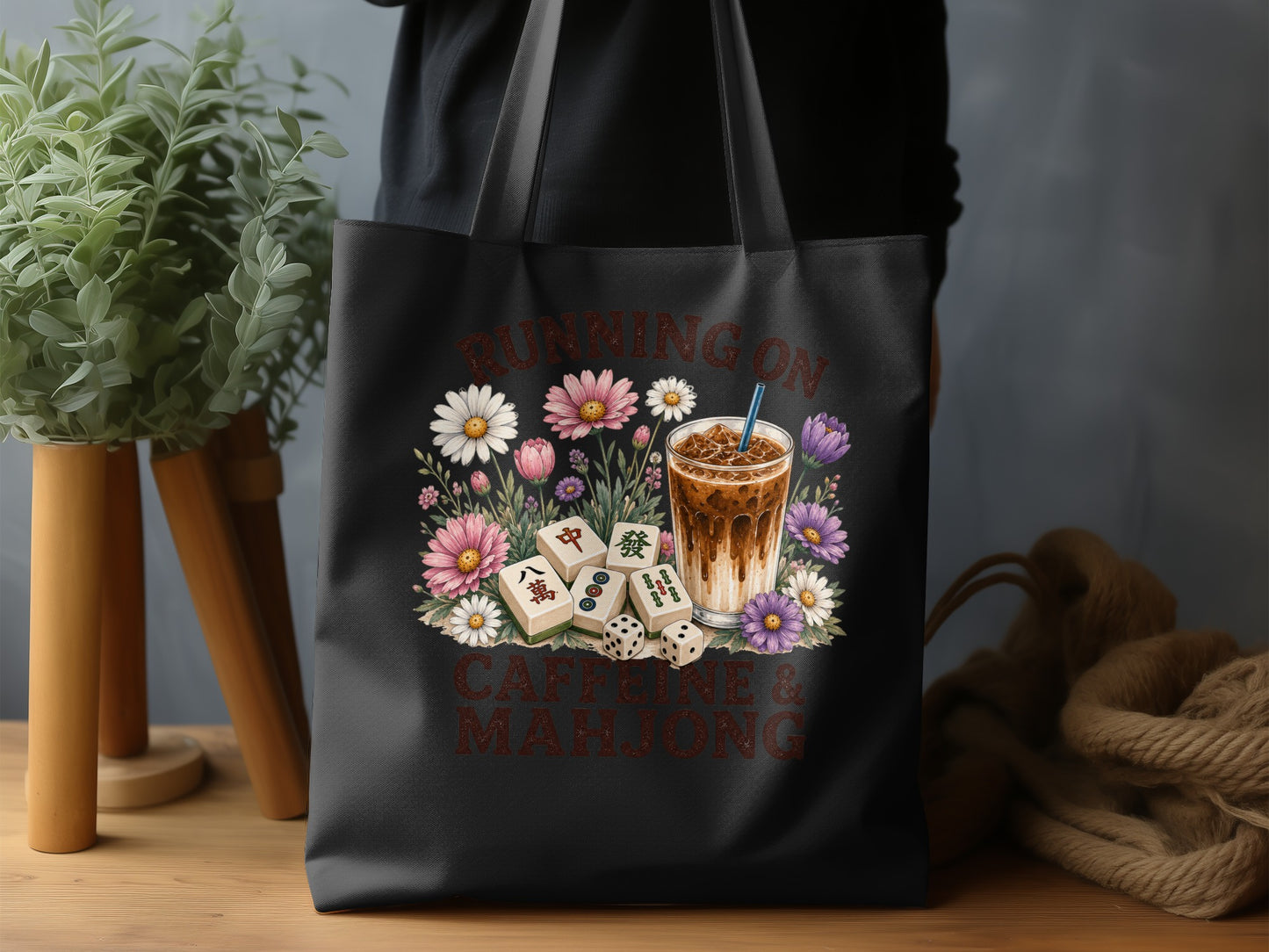Black tote bag with "Running on Caffeine & Mahjong" and floral design.