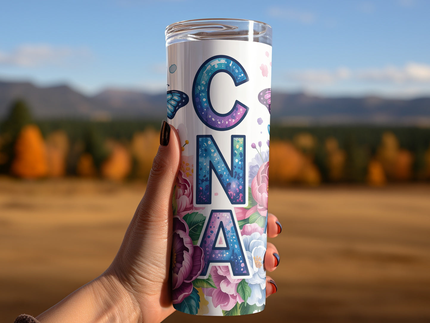 Tall tumbler with colorful floral design and butterflies, held by a hand.