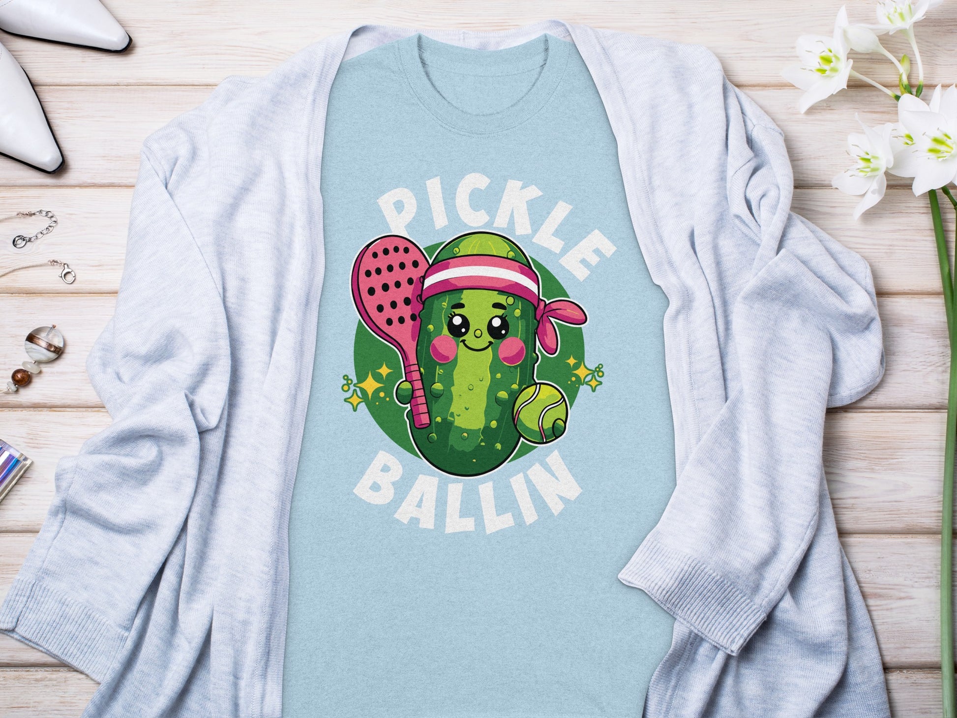 Pickleball cartoon with a smiling pickle, paddle, and ball.