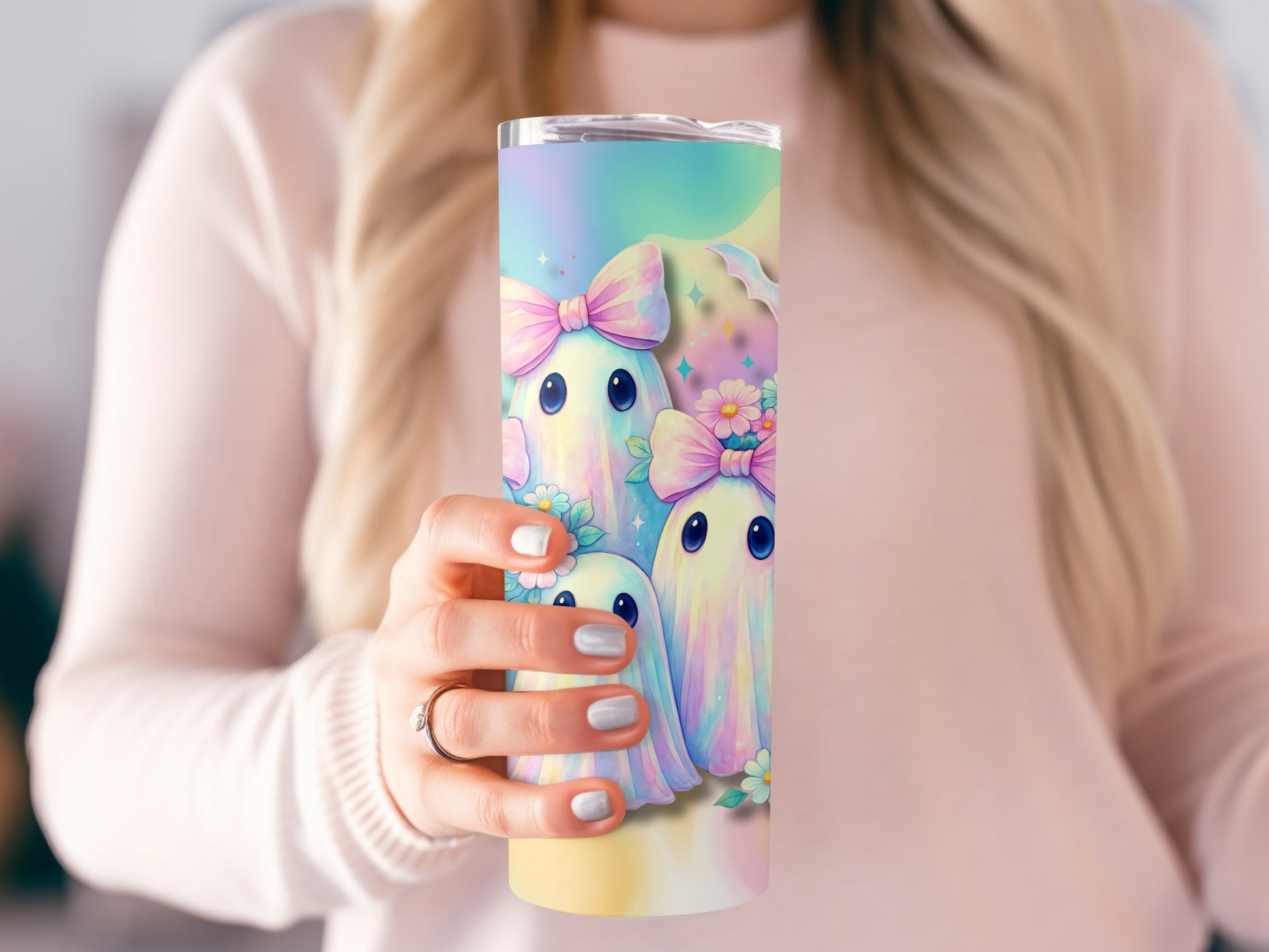 Tumbler with pastel ghosts and bows, held by a person.
