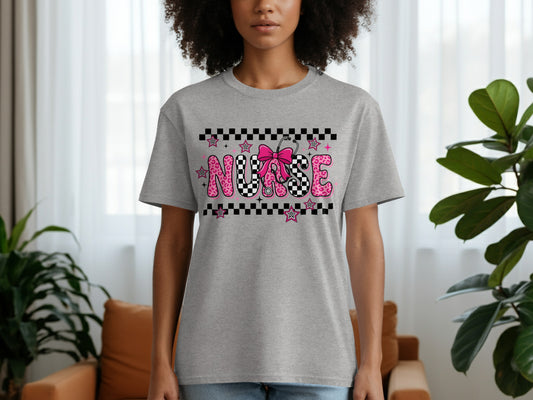Grey t-shirt with "NURSE" text in pink checkerboard and star pattern.