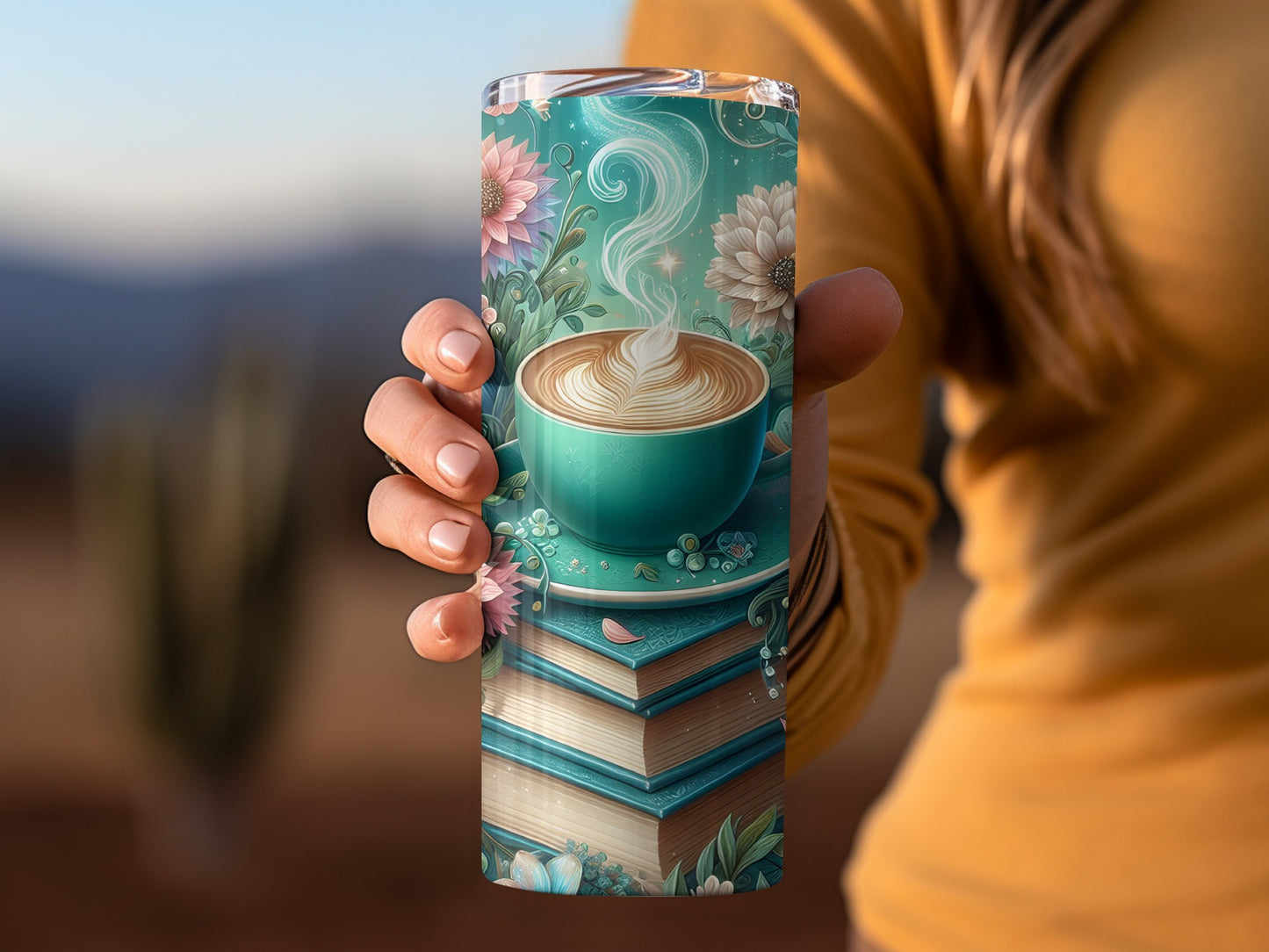 Hand holding a teal mug of coffee on a stack of books, floral accents.