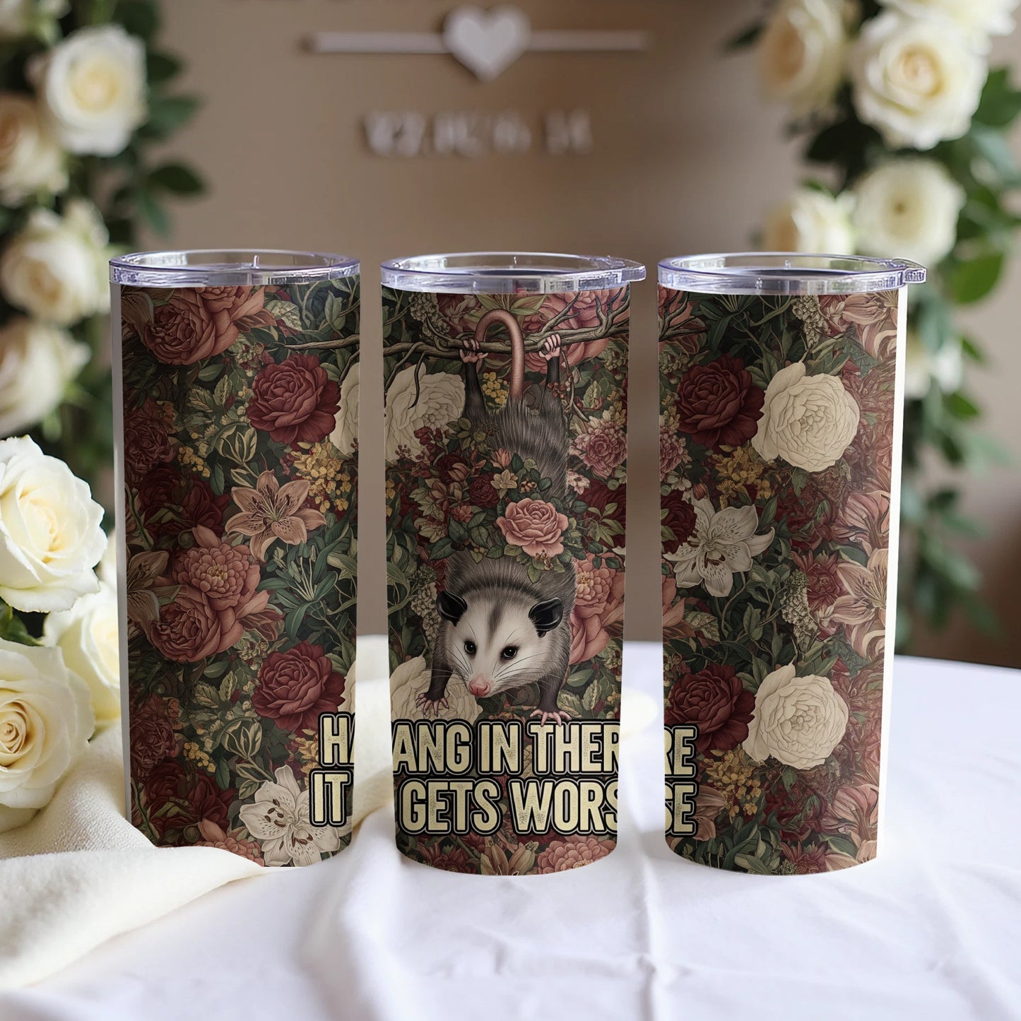Tapestry-patterned tumbler with opossum hanging upside down, saying "Hang in there, it gets worse".