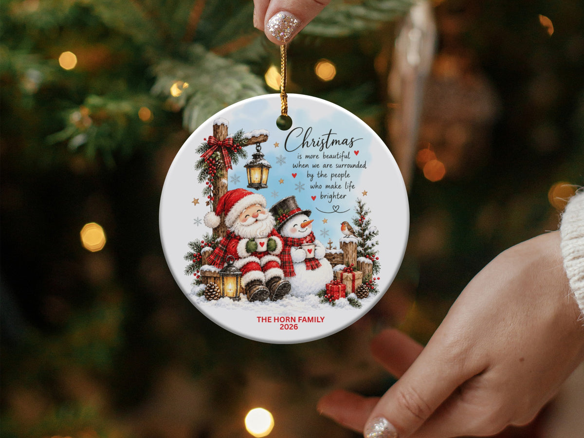 Round ceramic Christmas ornament depicting Santa and a snowman with text and family name.