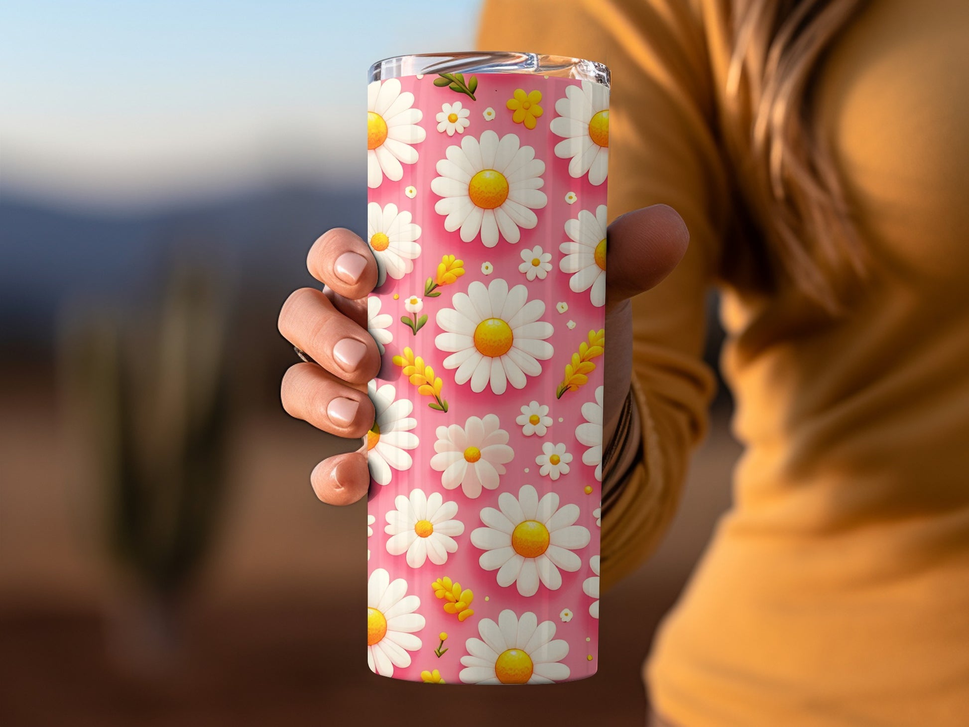 Hand holding a pink tumbler with a white daisy flower pattern.