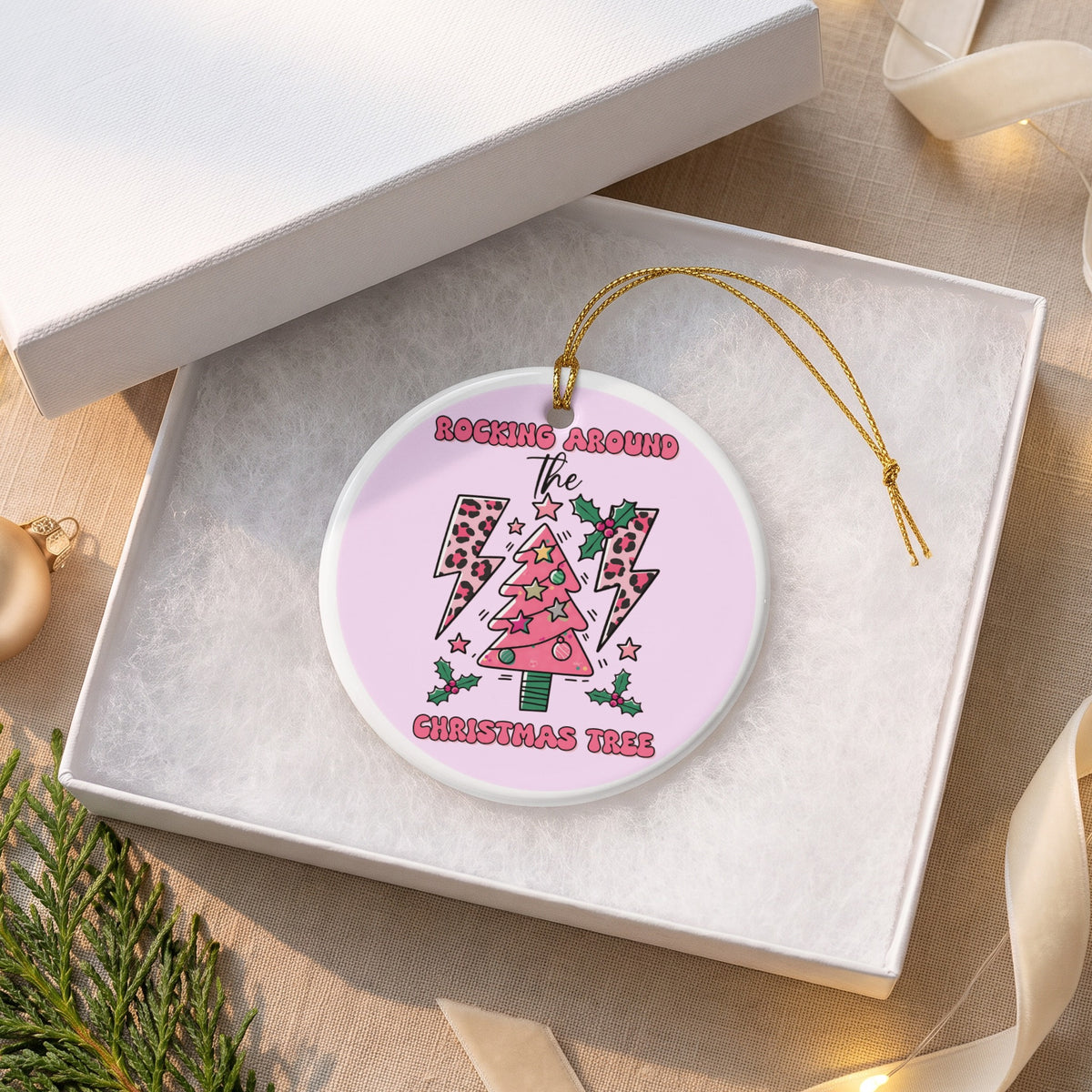 Round ornament with pink Christmas tree, stars, and lightning bolts.