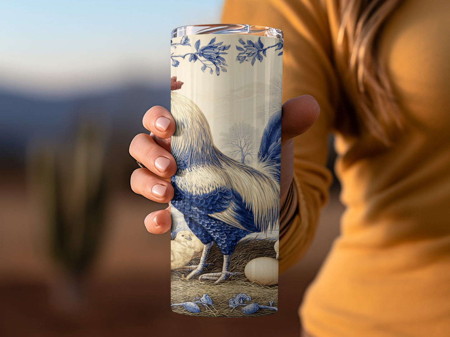Rooster, hens, and eggs pattern on a blue and white ceramic tumbler.