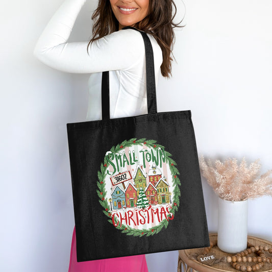 Black tote bag with a Christmas village graphic reading "Small Town 31602 Christmas".