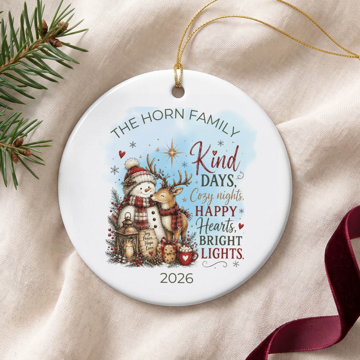 Round ceramic Christmas ornament featuring a snowman and reindeer illustration, personalized text, and the year 2026.