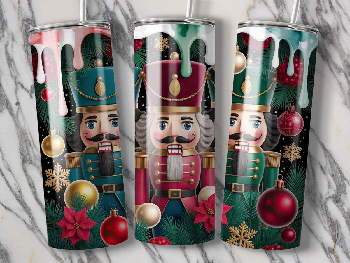 Three tall cylindrical tumblers display a Christmas nutcracker design with ornaments, pine needles, and dripping paint on a marble background.