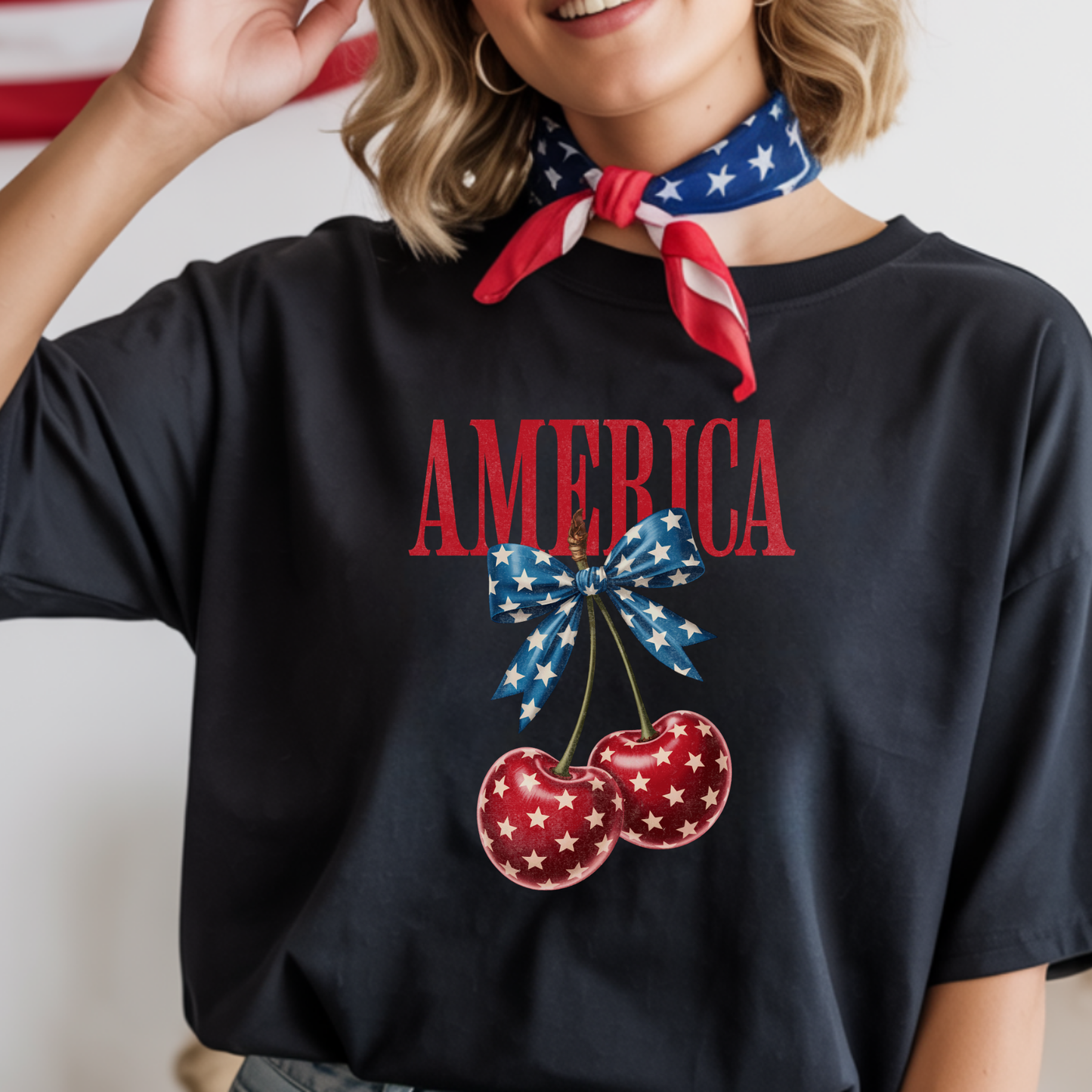 Person wearing a black t-shirt with 'AMERICA' and cherry design, holding a red, white, and blue scarf.