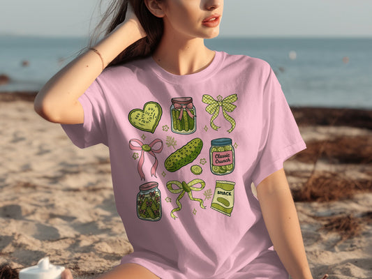 Pink t-shirt with graphics of pickles in jars and packaging.