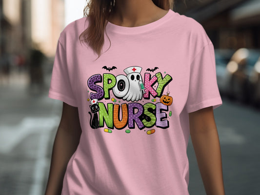 Pink t-shirt with "Spooky Nurse" graphic featuring bats, syringe, and pumpkin.