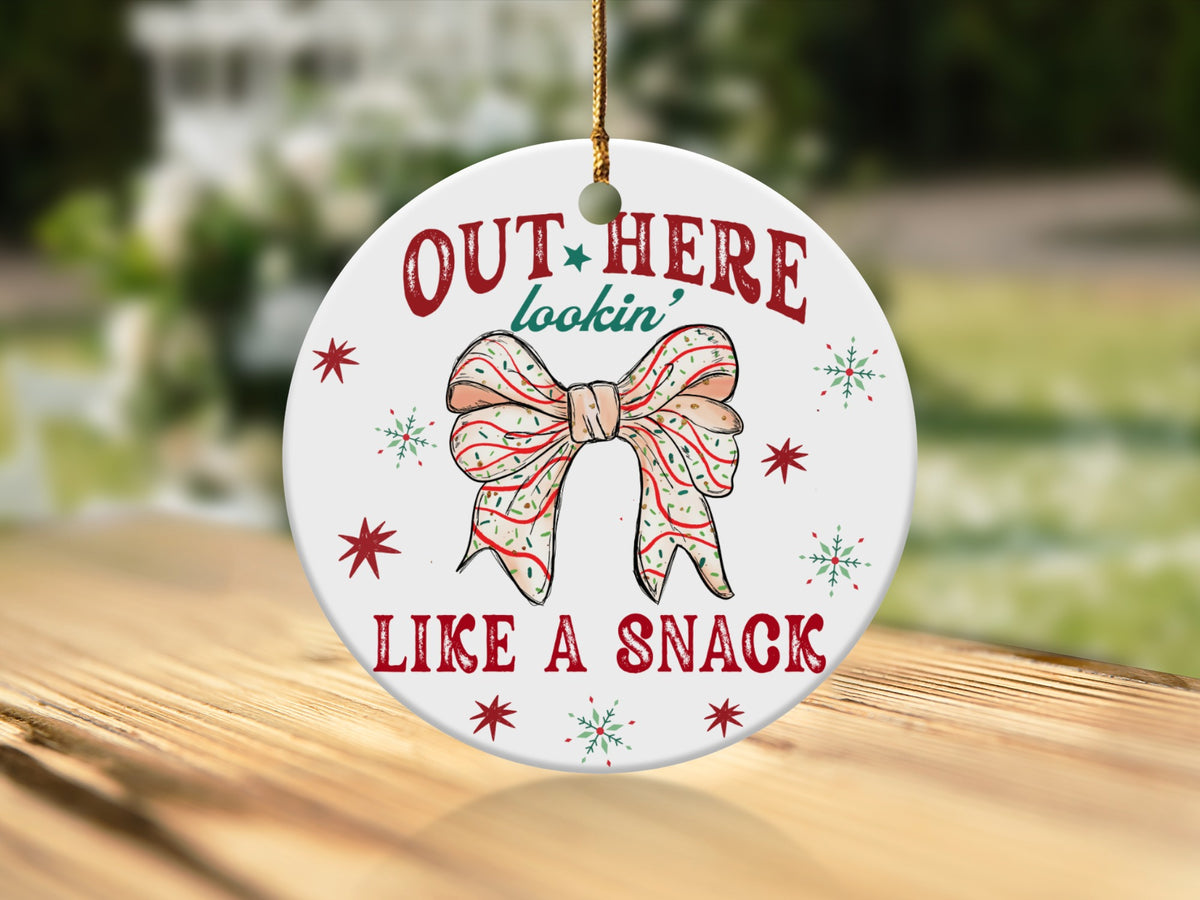 Round ceramic ornament with bow graphic and text "OUT HERE lookin' LIKE A SNACK".