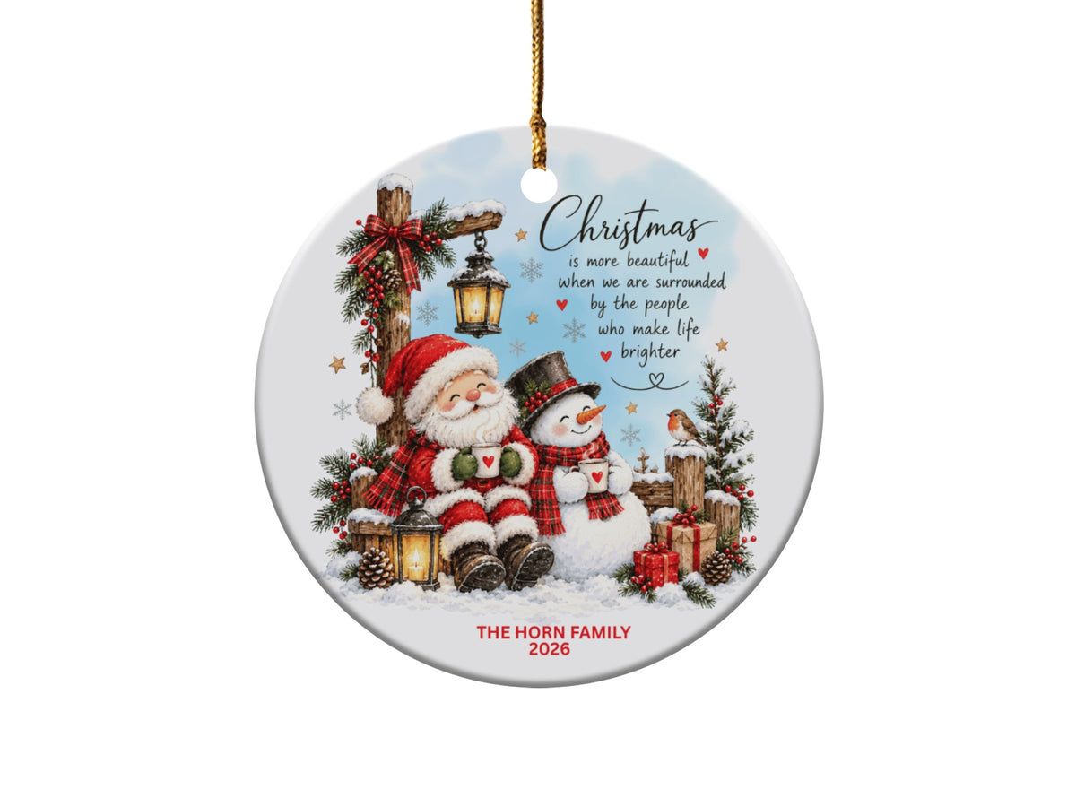 Round ceramic Christmas ornament featuring Santa and a snowman holding mugs, with personalized text.