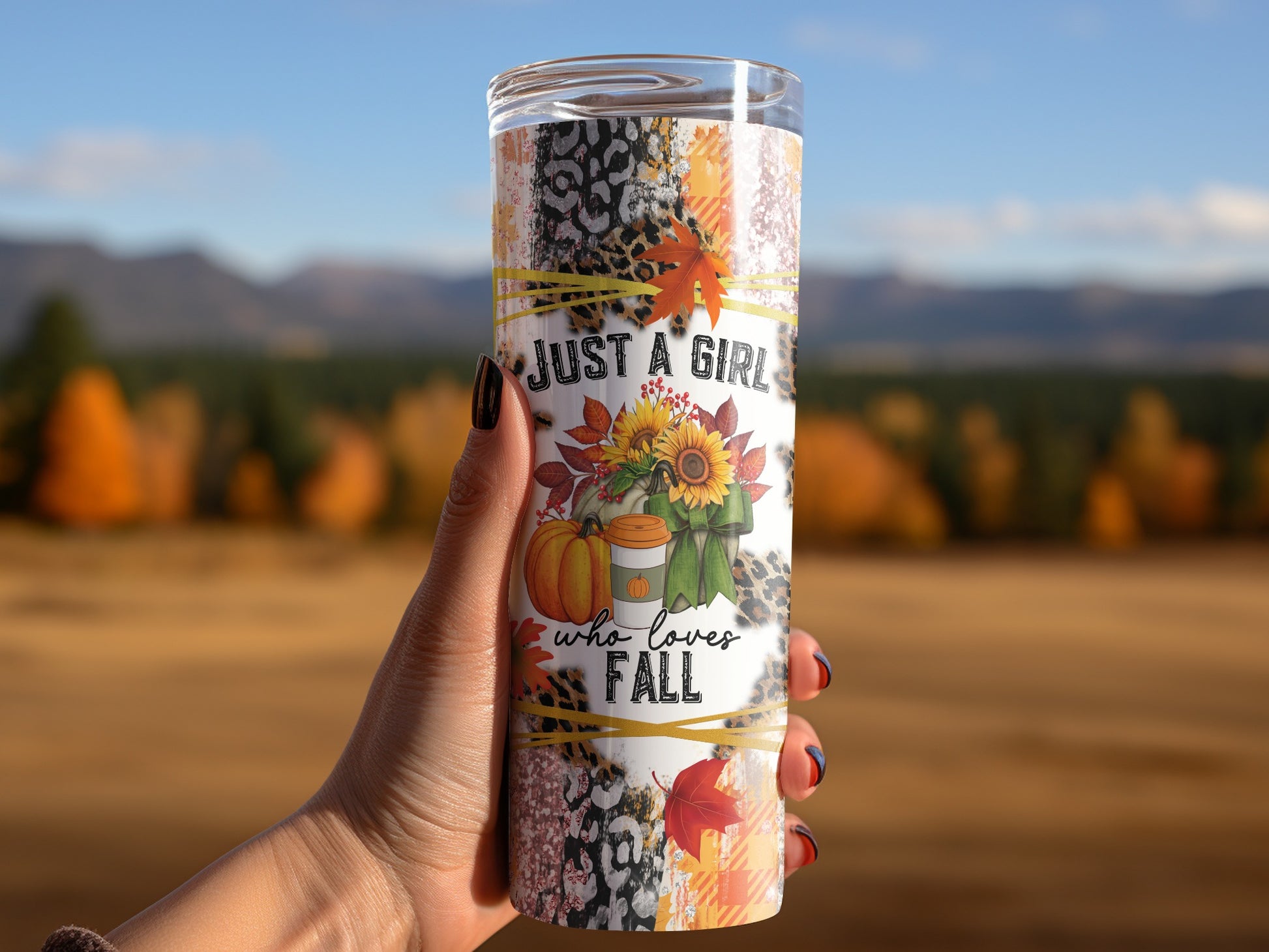 Tumbler with "JUST A GIRL who loves FALL" text and autumn graphics held by a hand.