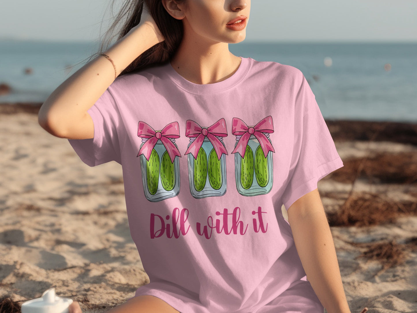Pink t-shirt with three jars of pickles adorned with pink bows, text "Dill with it".
