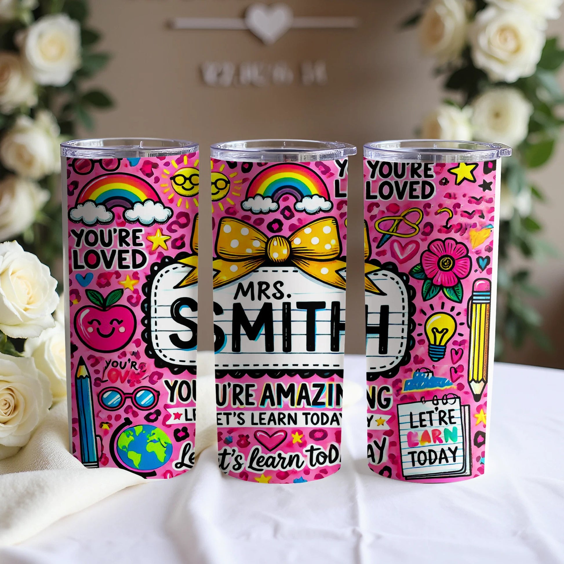 Pink tumbler with "You're Loved," "You're Amazing," and "Let's Learn Today" text and school-themed graphics.