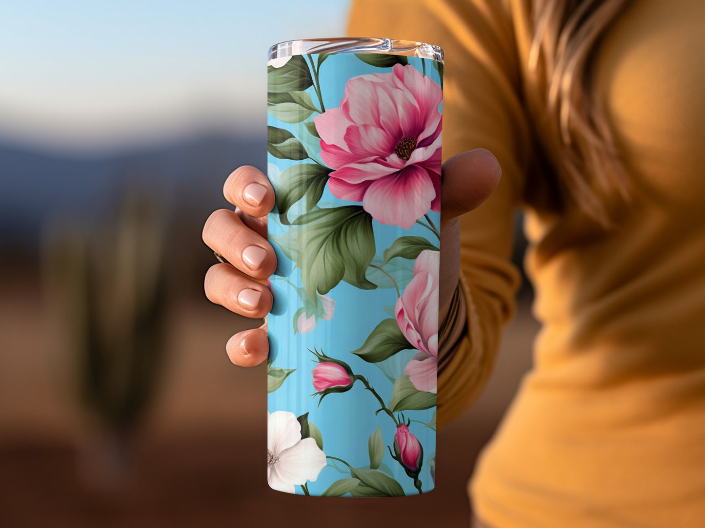 Floral tumbler with pink magnolias and green leaves on blue background.