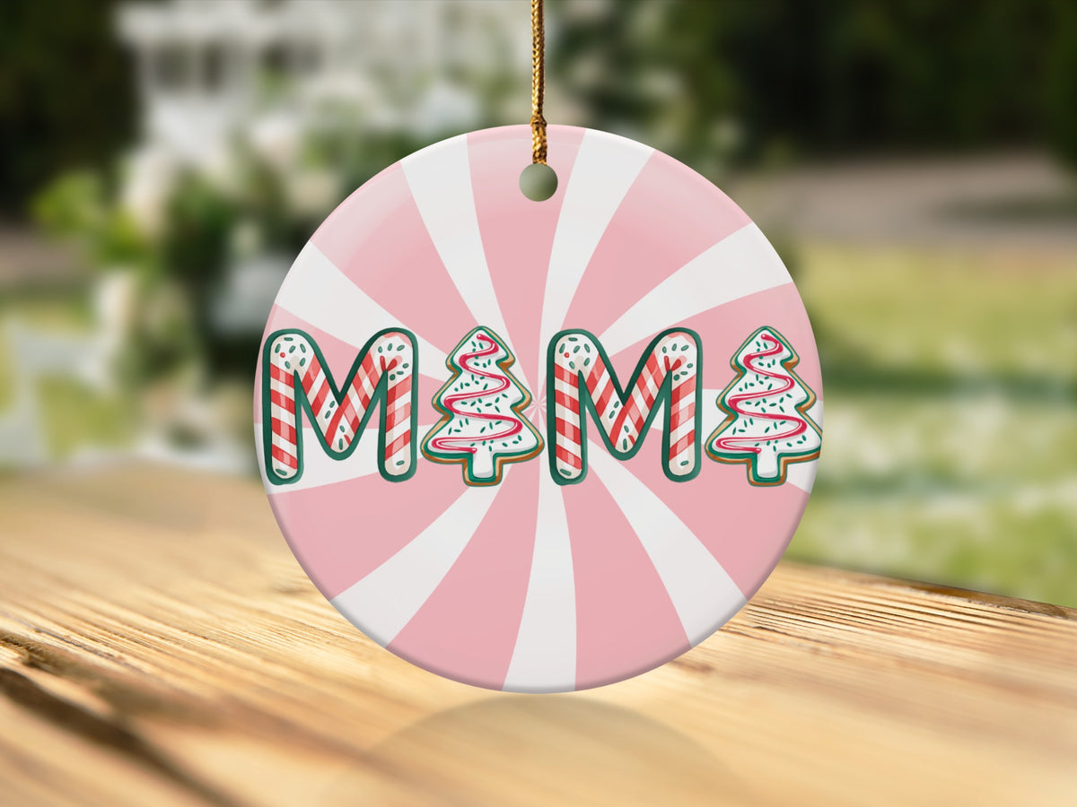 Round Christmas ornament with "Mama" text in cookie shapes on a pink and white background.