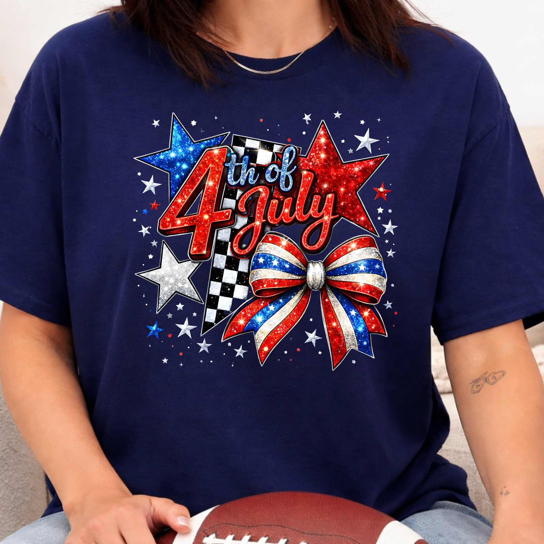 Navy blue t-shirt with '4th of July' design featuring stars and a bow, held by a person.