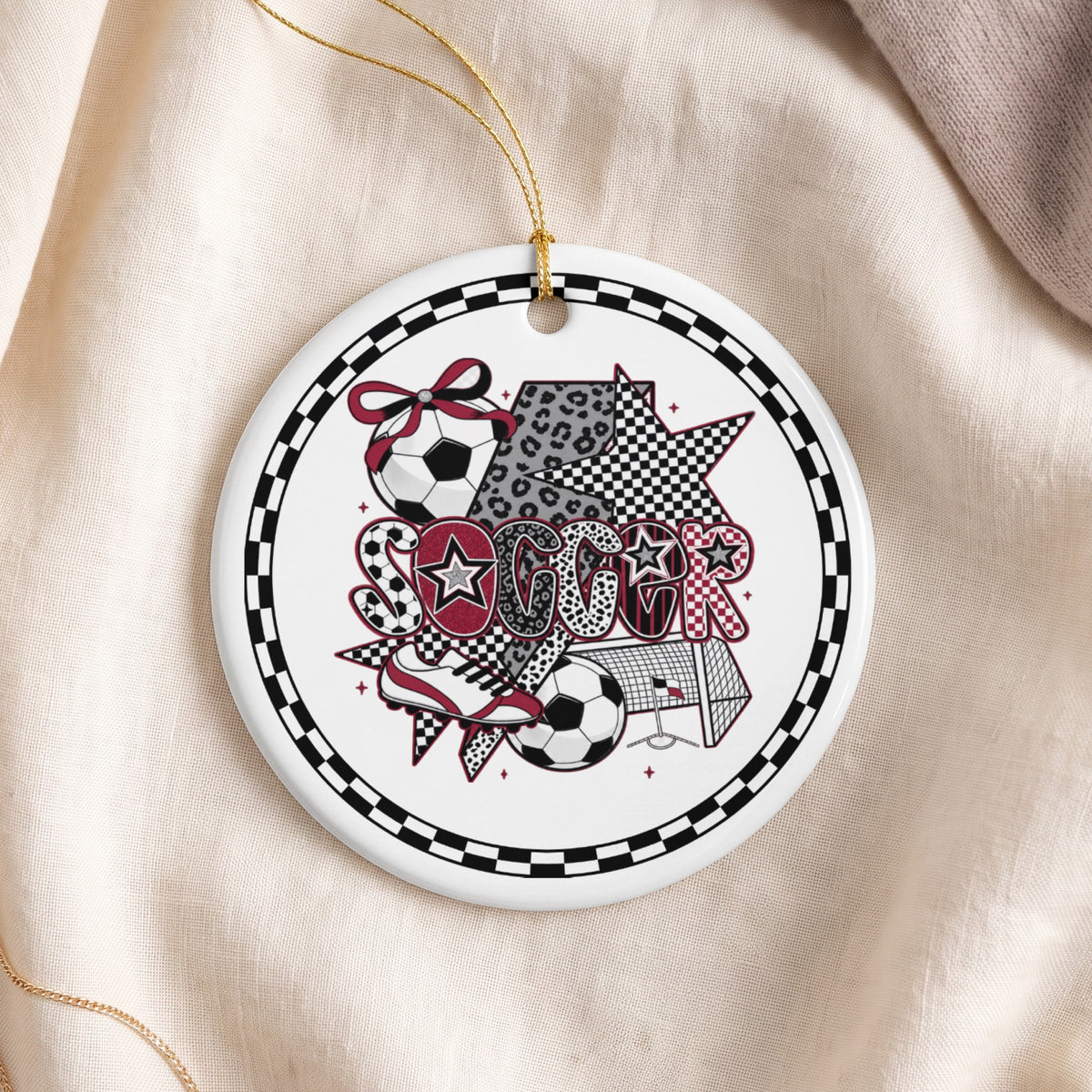 Round ornament with "SOCCER" text and soccer ball graphics, presented on fabric.