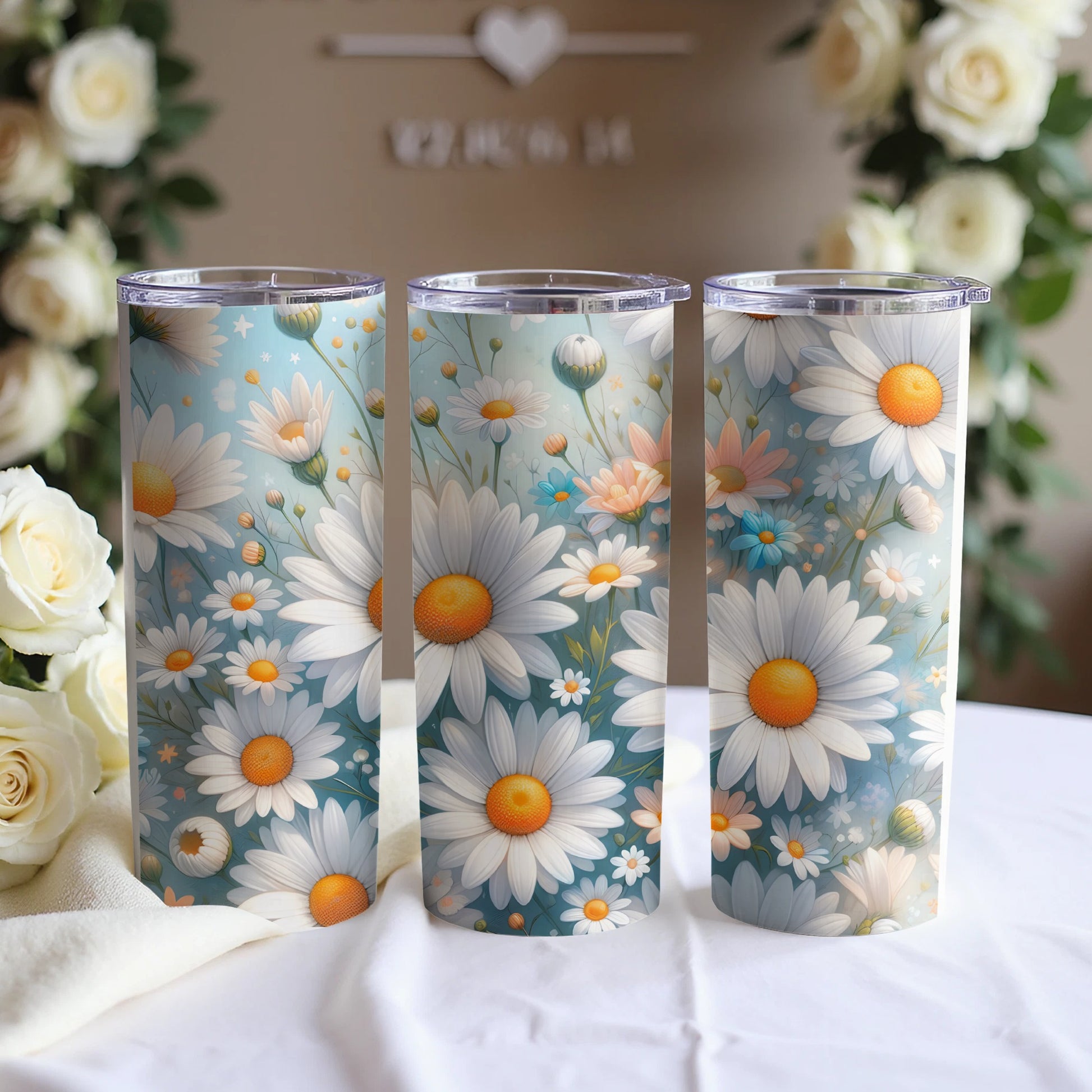 Three tumblers with a pastel floral daisy pattern displayed on a white cloth.
