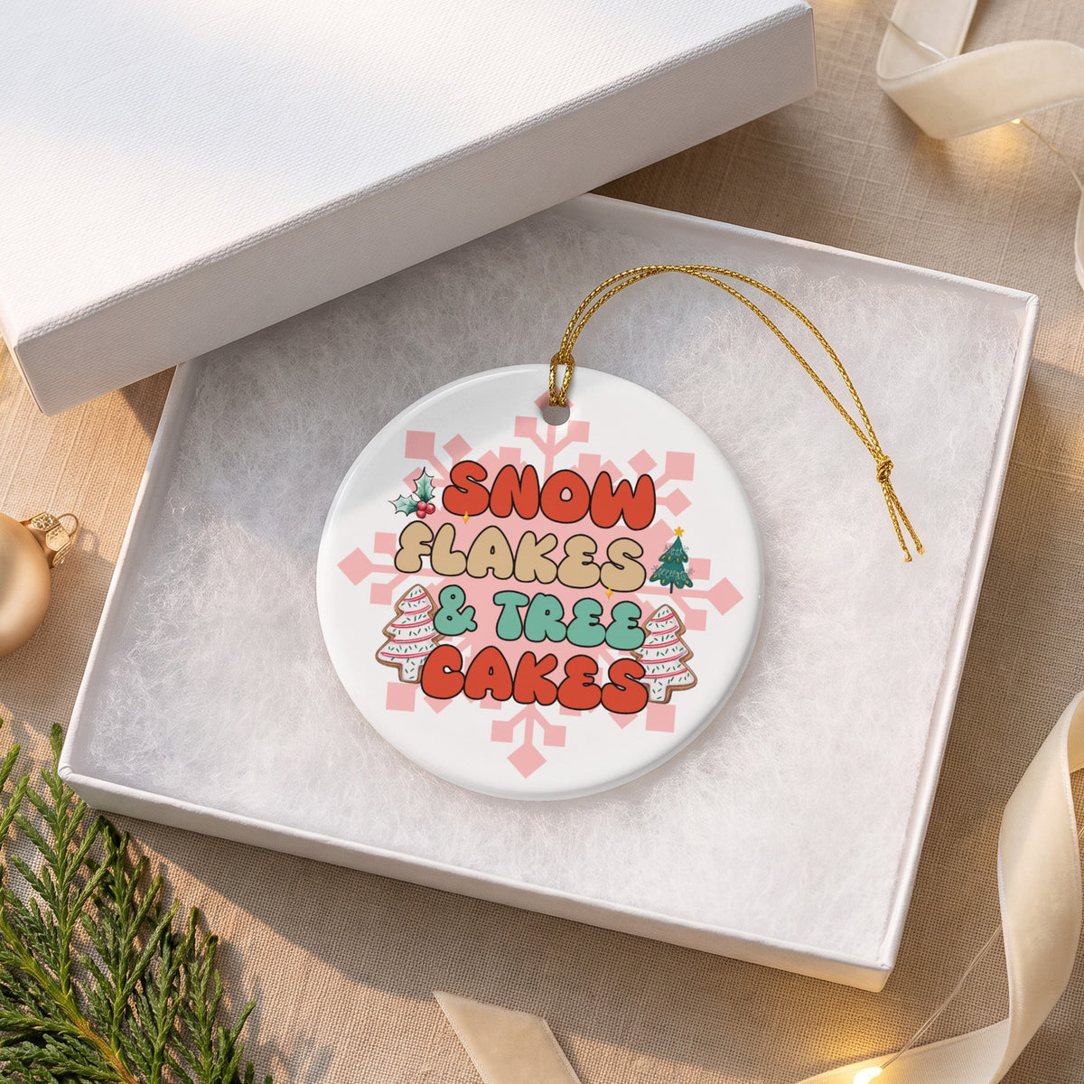 Round ornament with text "SNOW FLAKES & TREE CAKES" and festive graphics.