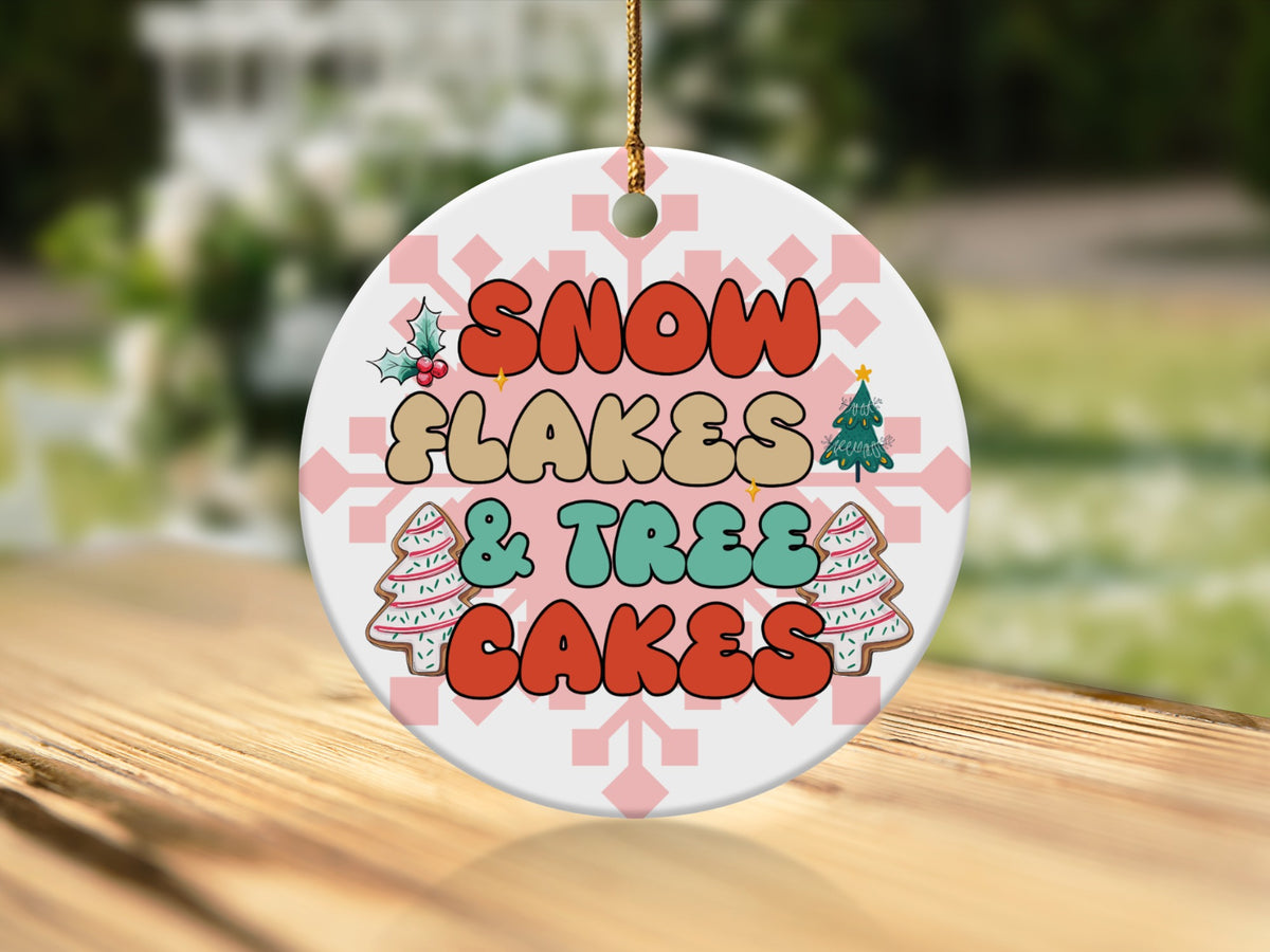 Round Christmas ornament with "Snow Flakes & Trees Cakes" text, holly, and gingerbread trees.