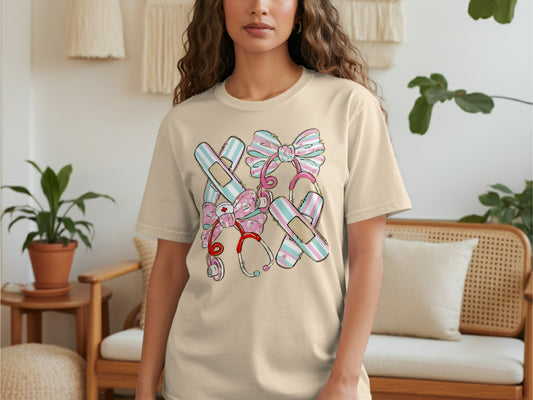 Light beige t-shirt with a graphic of medical supplies and pink bows.