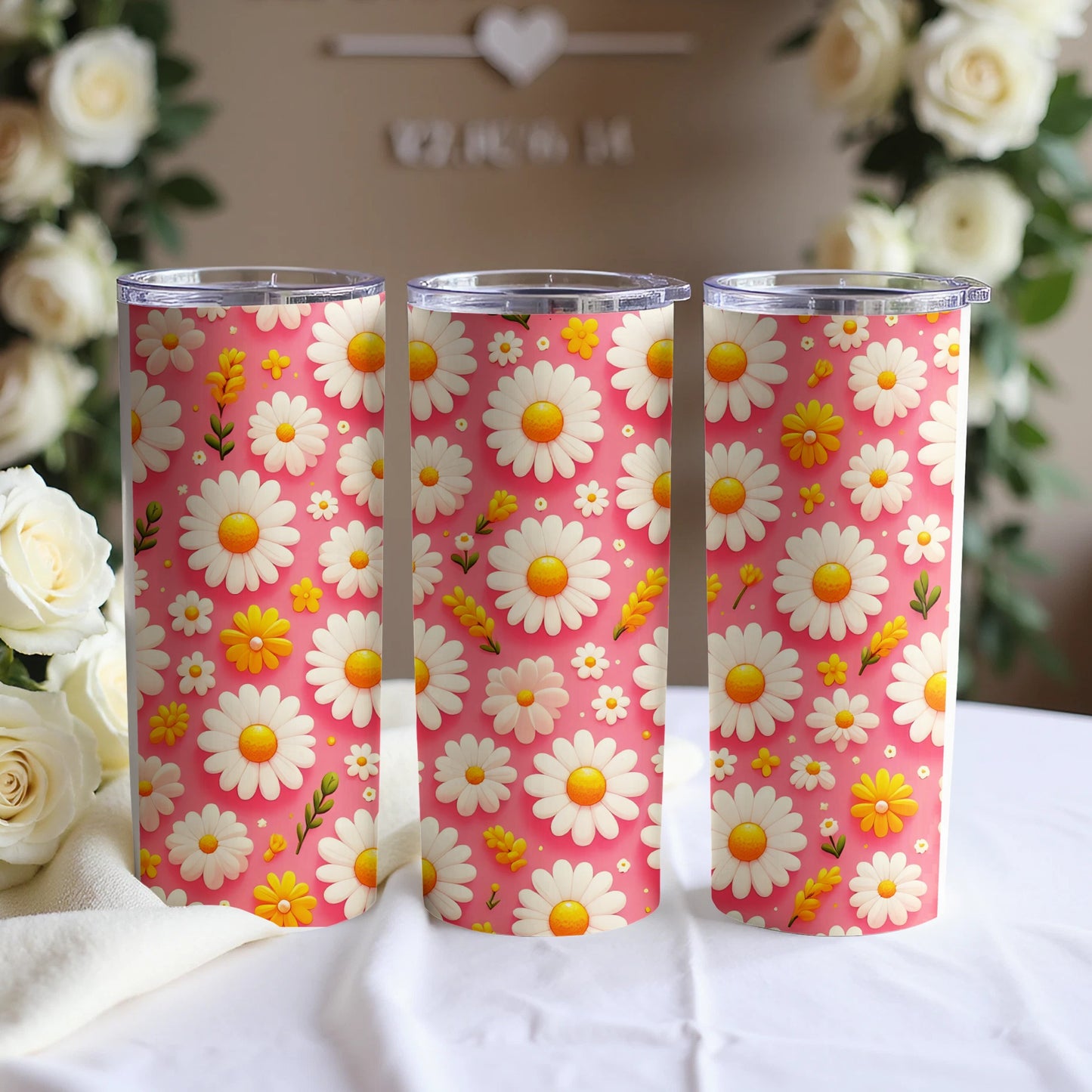Three pink tumblers with a repeating daisy floral pattern.