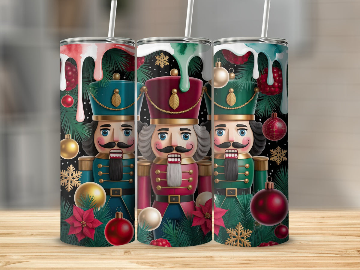 Three tall tumblers with Christmas nutcracker designs, pine branches, ornaments, and dripping paint on a wooden table.