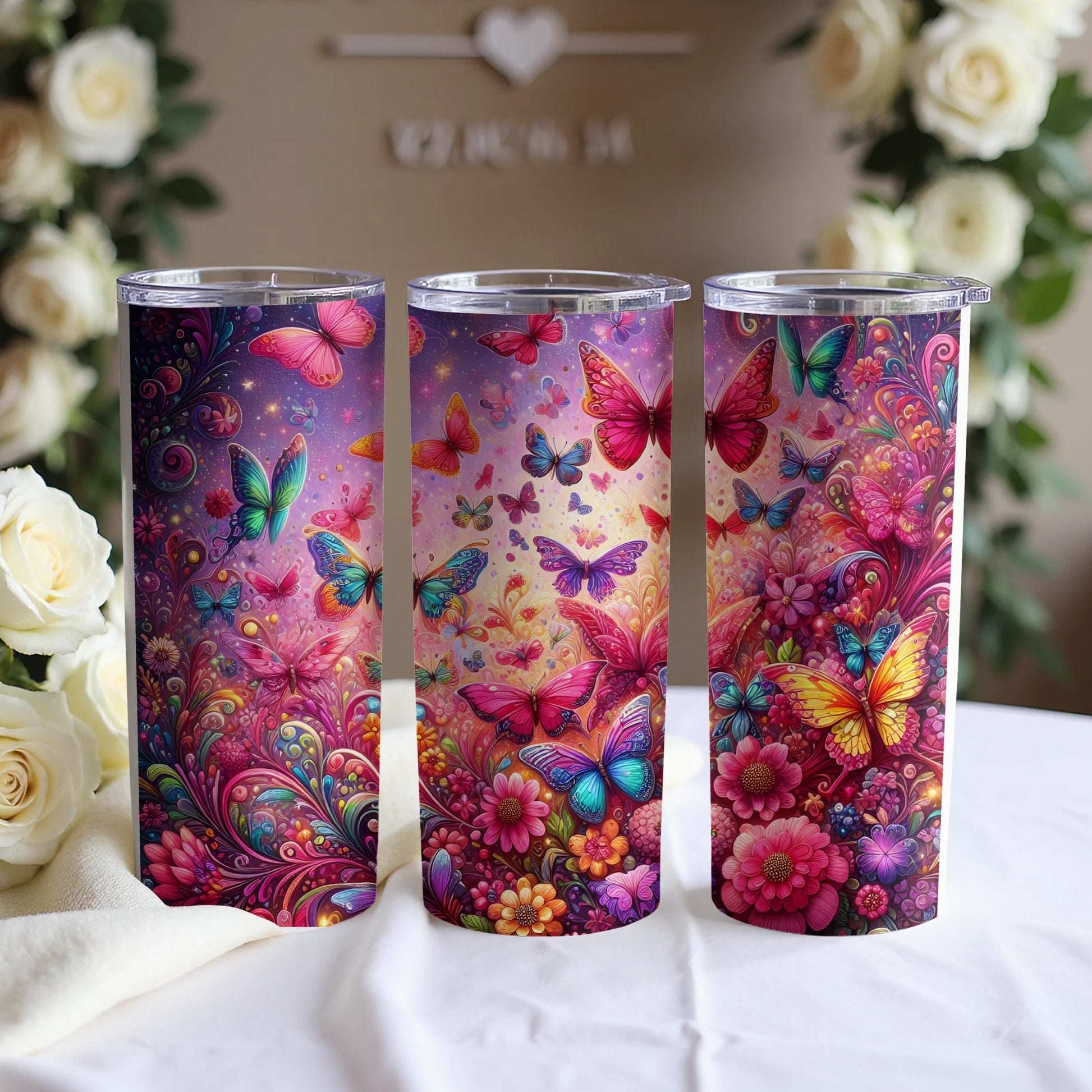 Three tumblers decorated with colorful butterflies and floral designs.