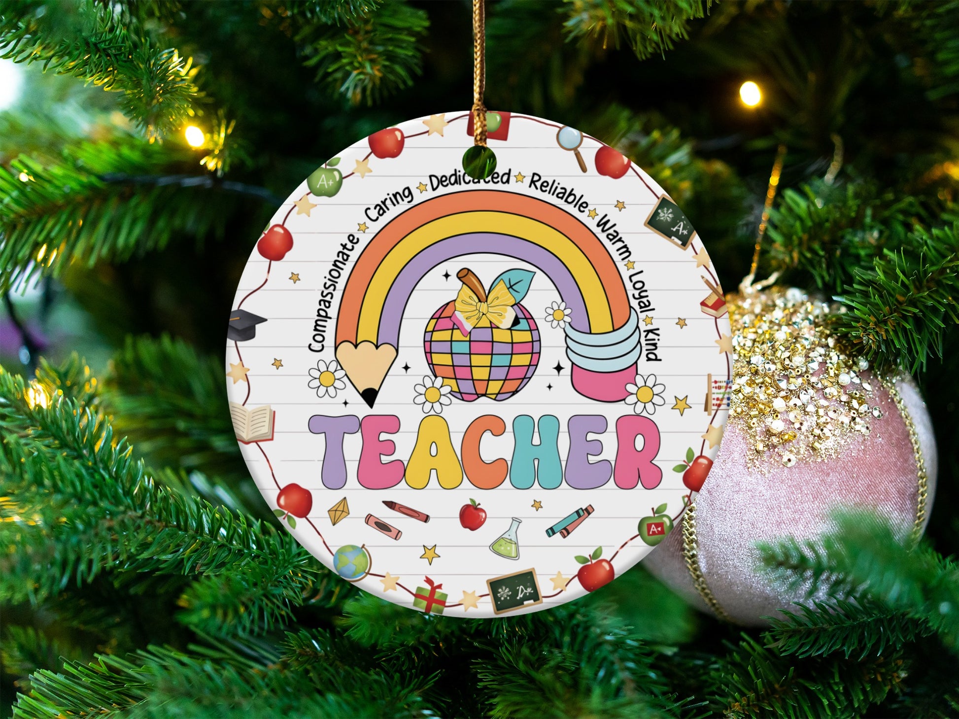 Round ceramic ornament with "TEACHER" text, rainbow, and school icons on Christmas tree.