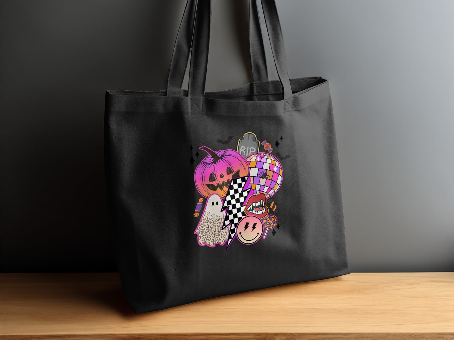 Black tote bag with a collage of Halloween icons including a pumpkin, ghost, and disco ball.