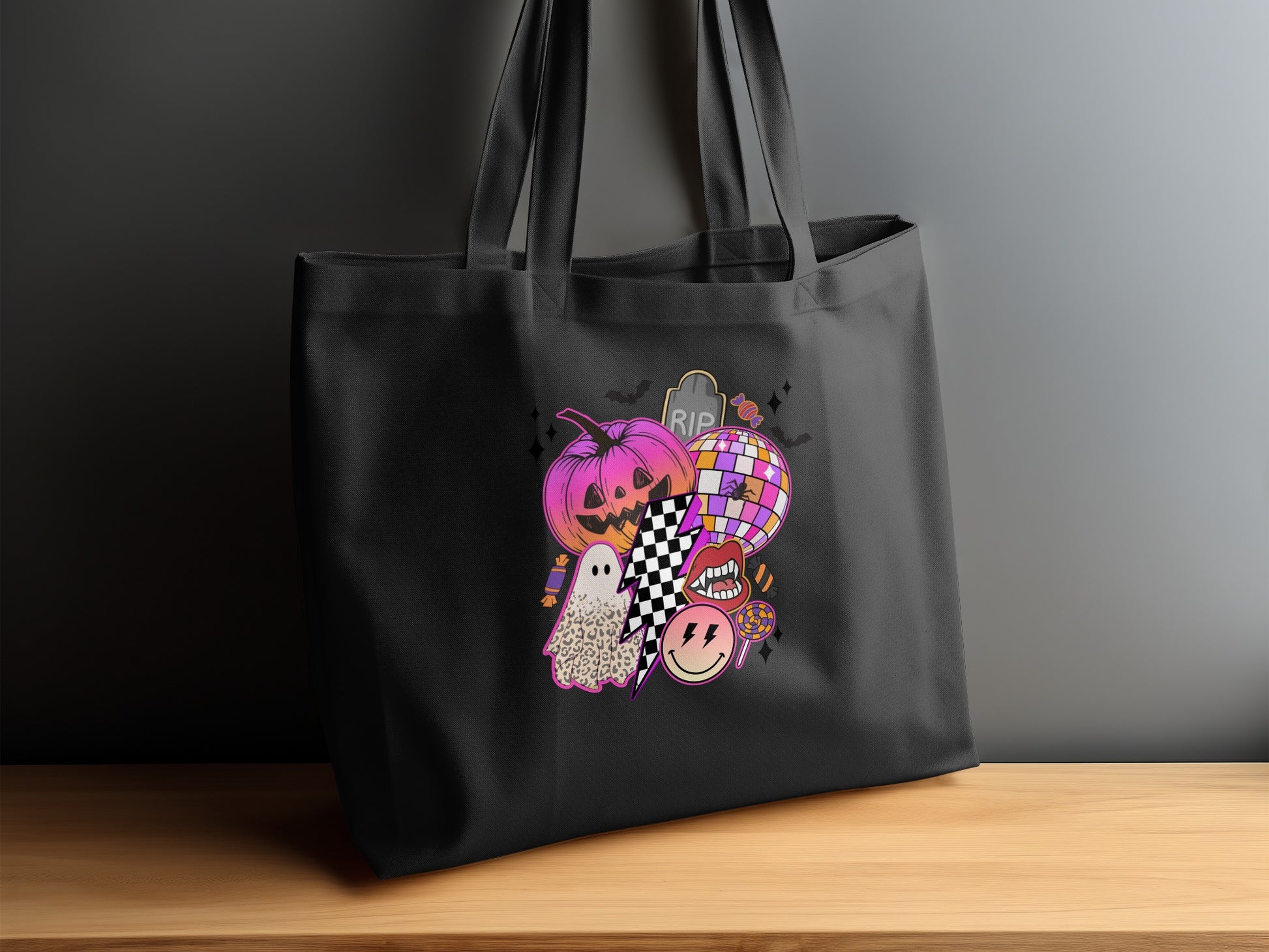 Black tote bag with a collage of Halloween icons including a pumpkin, ghost, and disco ball.