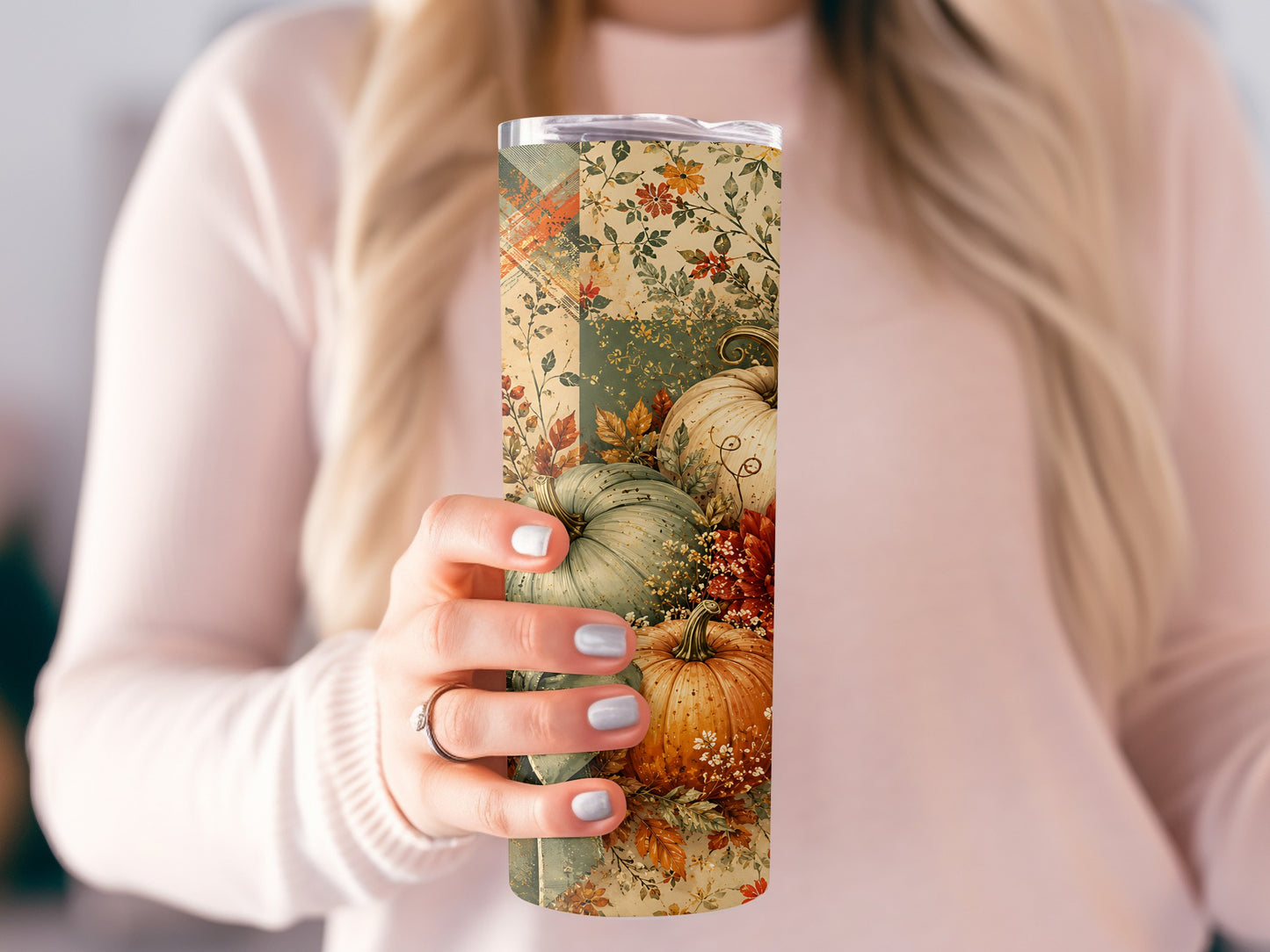 Tumbler with pumpkins and fall foliage pattern held by a person.