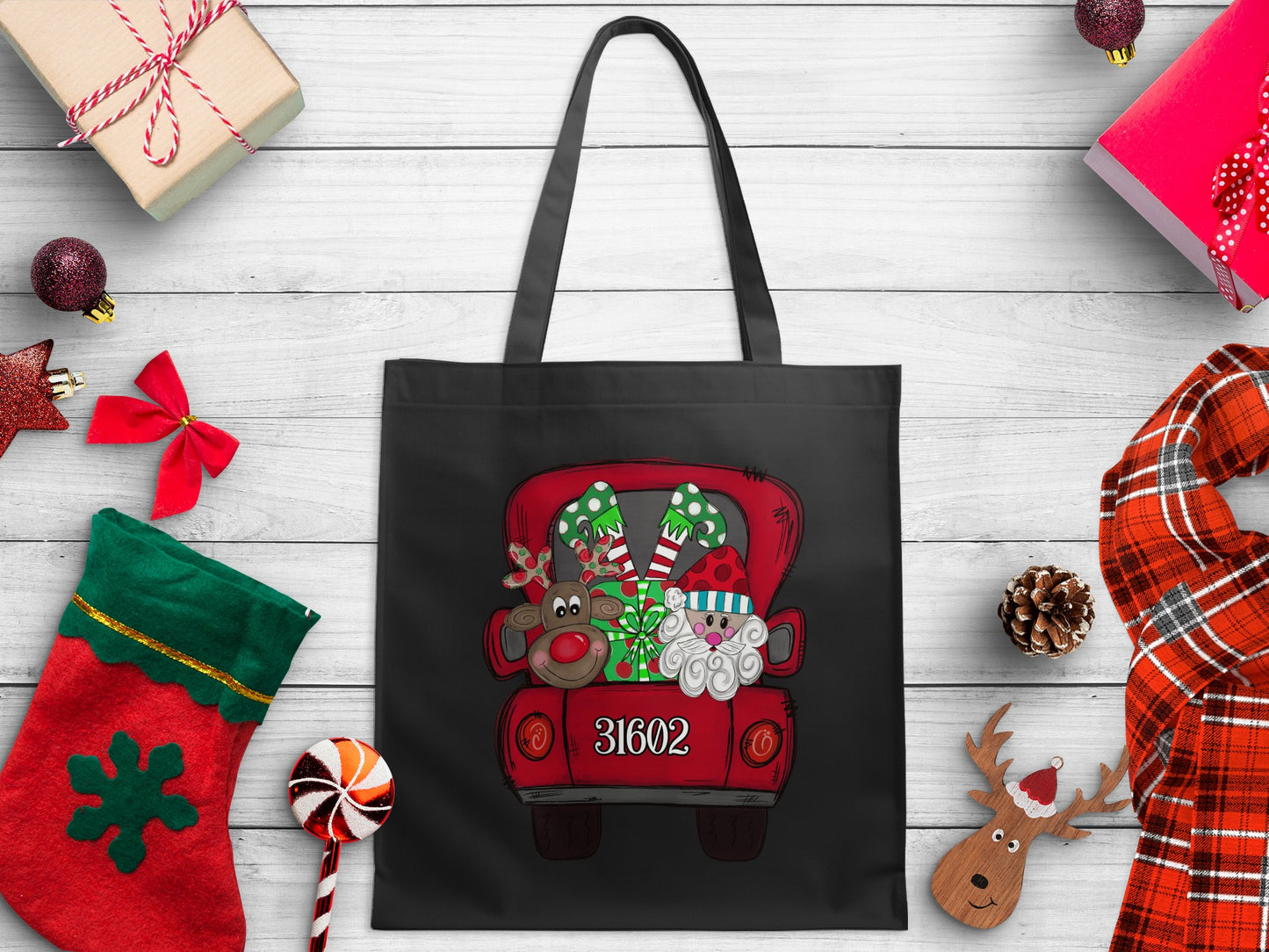 Black tote bag with Christmas art featuring Santa, reindeer, and gifts in a red truck with 31602.