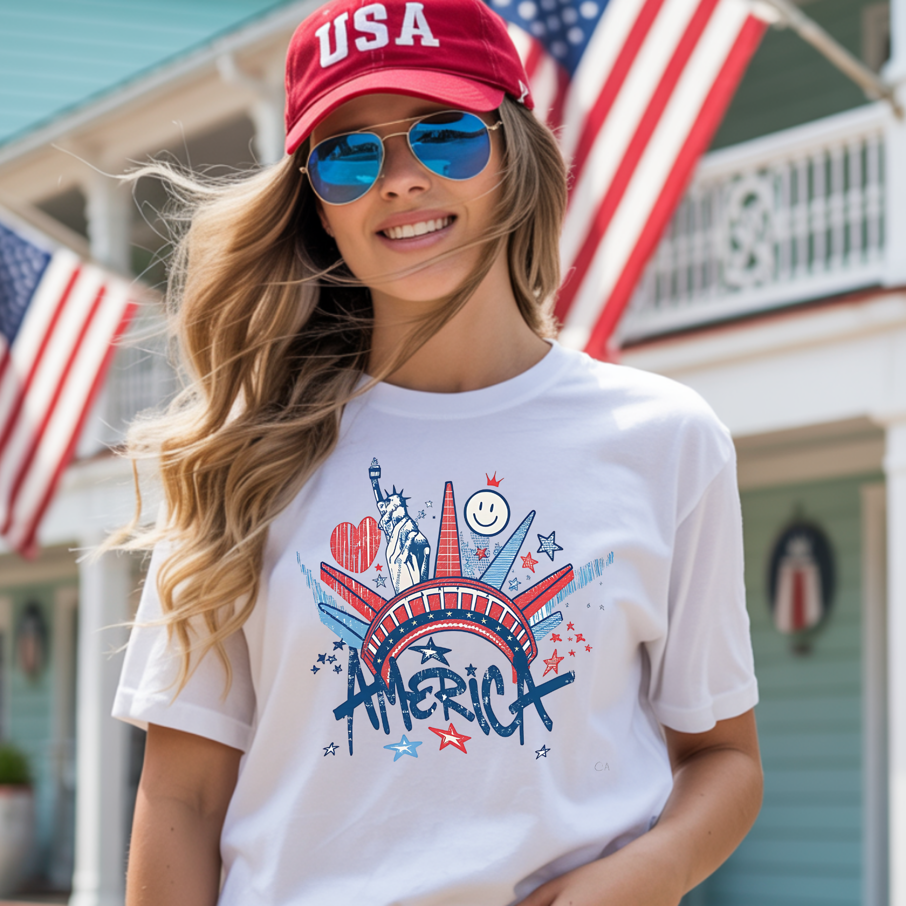 Woman wearing a white t-shirt with 'America' design and red cap with 'USA' text, standing in front of American flags.